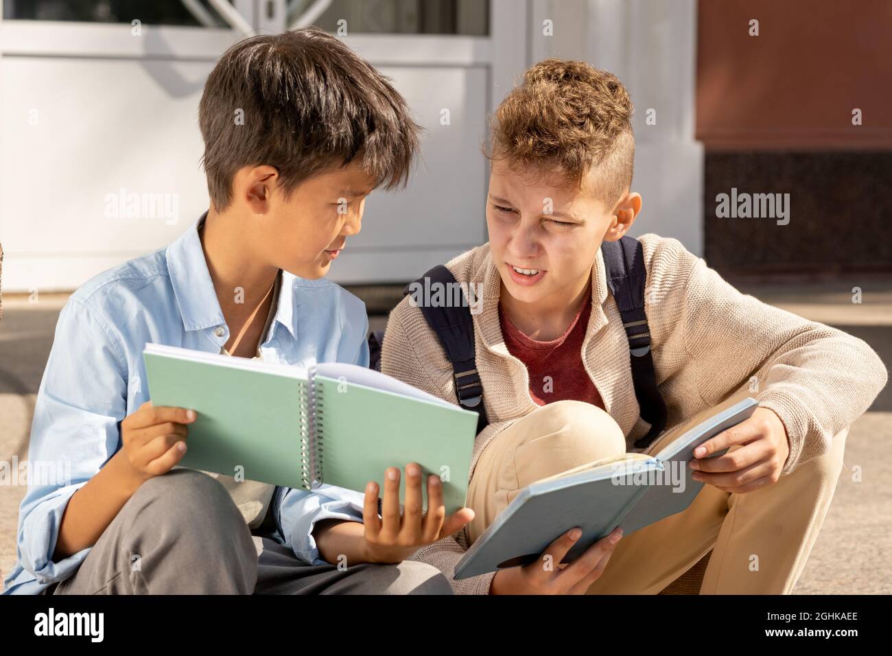 Deux écoliers discutant de leurs notes dans des copybooks avant ou après des leçons Banque D'Images