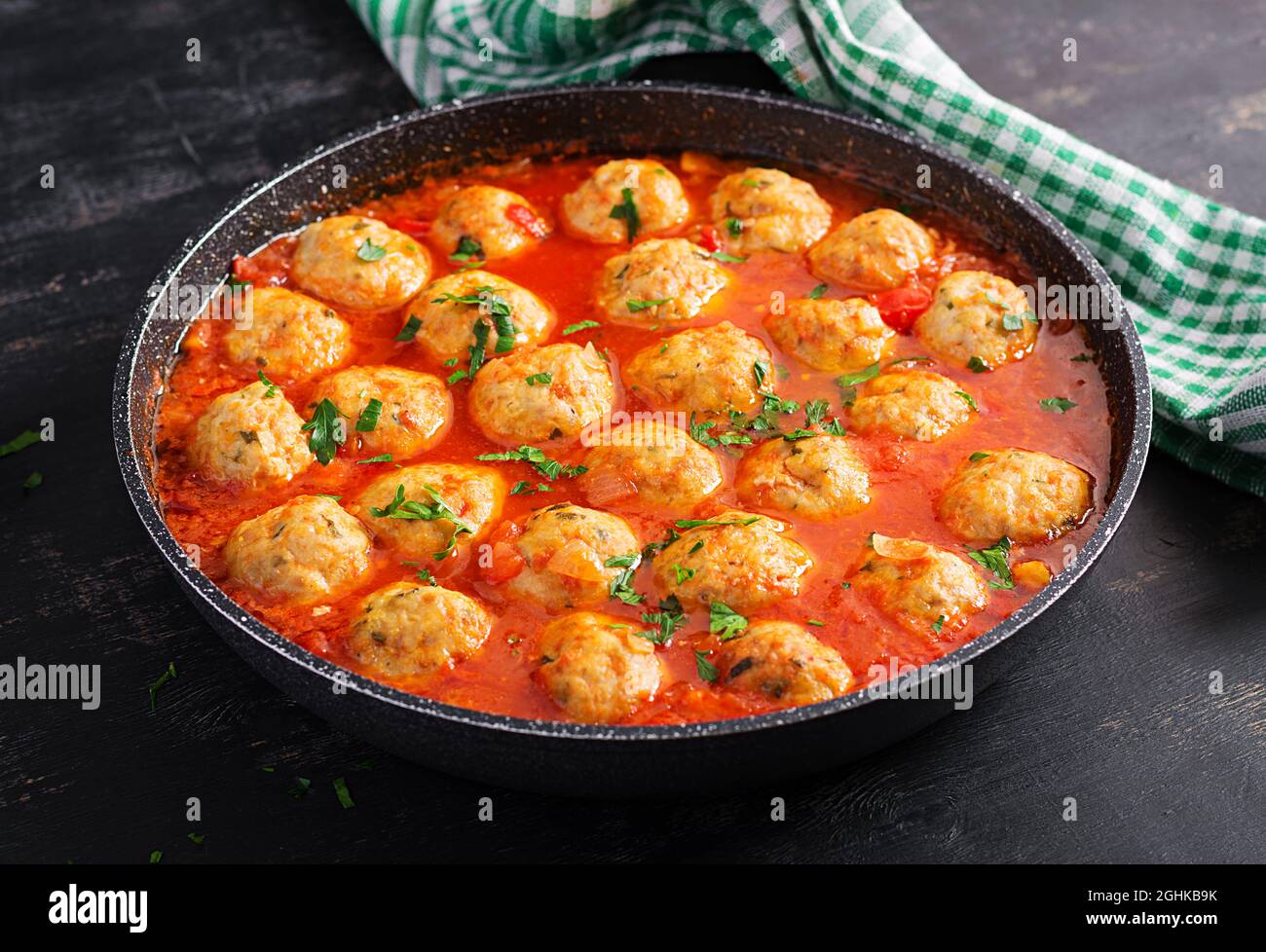 Boulettes de viande en sauce tomate dans une poêle sur fond sombre. Banque D'Images