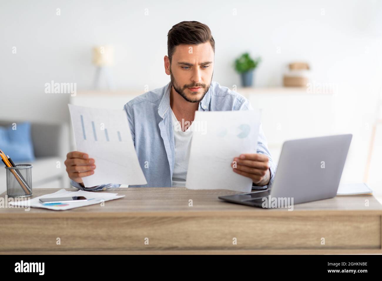 Auto-entrepreneur millénaire travaillant avec des papiers au bureau à domicile, vérifiant les rapports financiers annuels, espace libre Banque D'Images