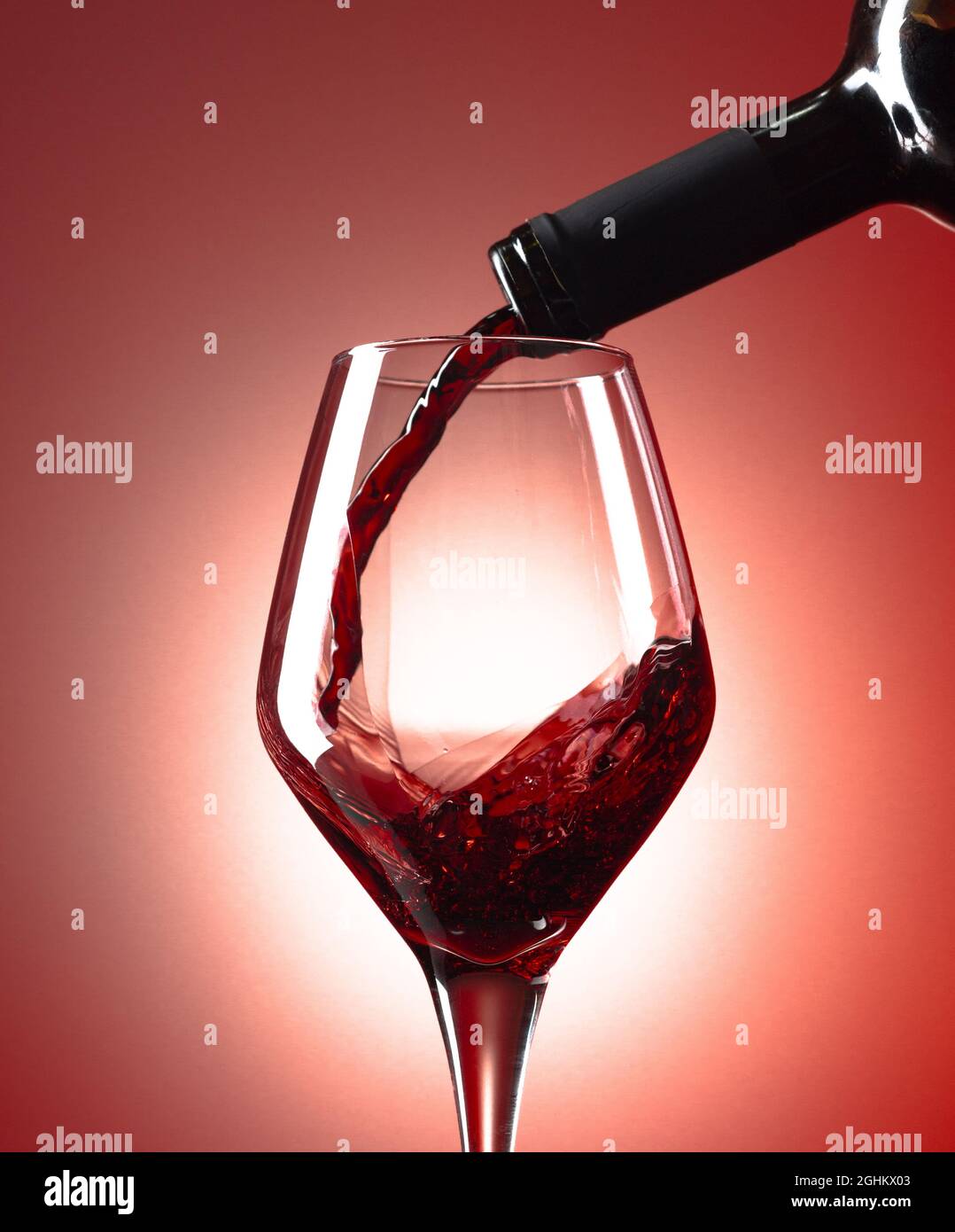 Le vin rouge est versé dans un verre de vin. Banque D'Images