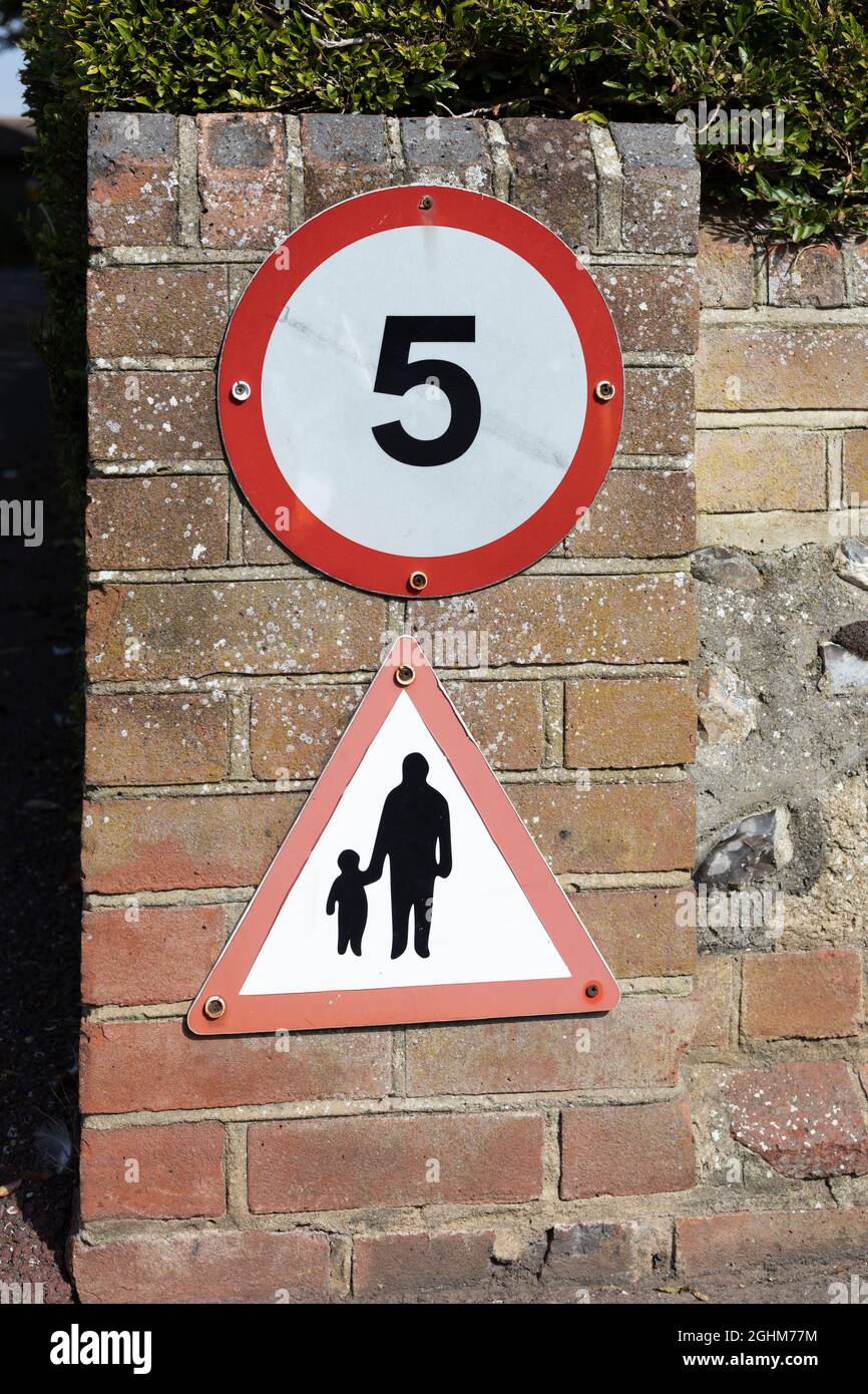panneau circulaire 5 km/h et panneau triangulaire piétons sur un mur de briques Banque D'Images