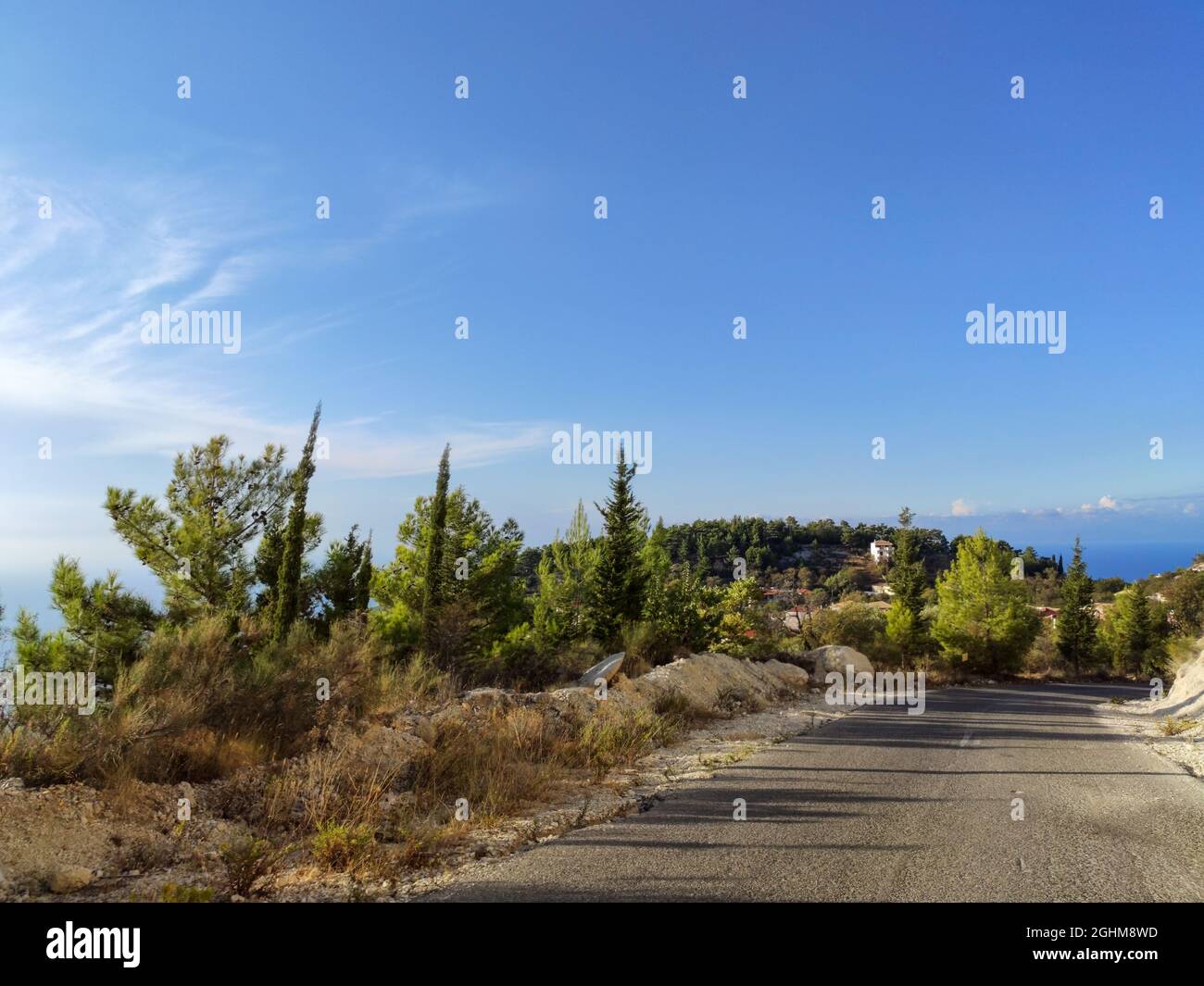 Route de montagne près du village de Kalamitsi avec ciel bleu clair, île de Lefkada, côte de mer Ionienne, Grèce. Excursion pittoresque d'une journée ensoleillée en été avec long sha Banque D'Images