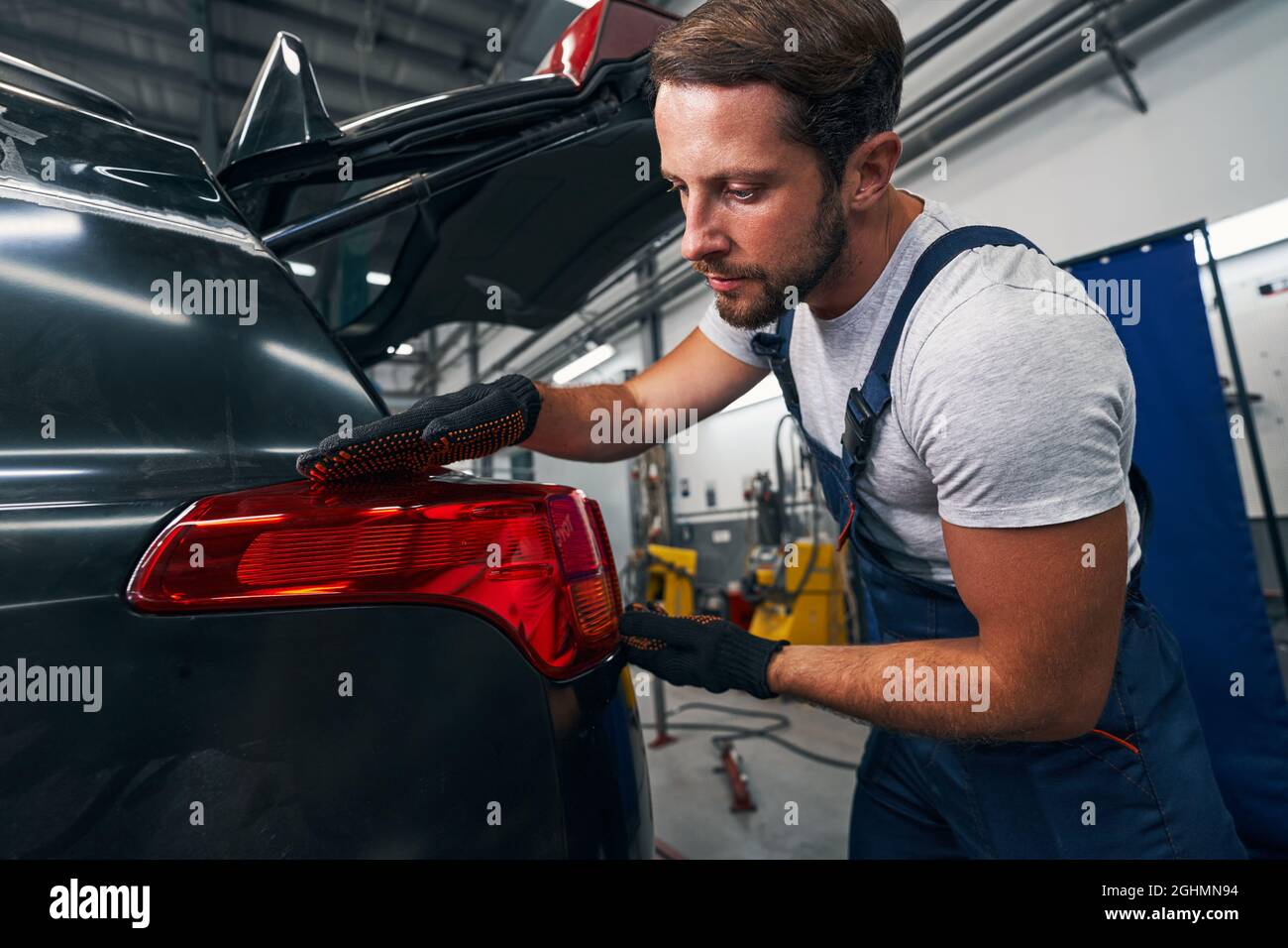 Un mécanicien de sexe masculin vérifie le niveau du feu arrière de la voiture Banque D'Images