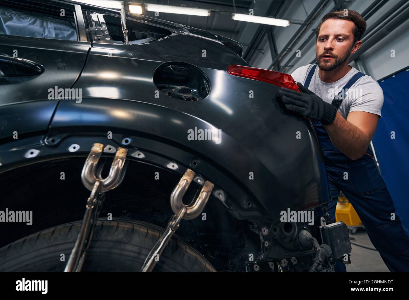 Les fixations à vis aplatiissent la carrosserie de la voiture pendant que le technicien règle le feu arrière Banque D'Images