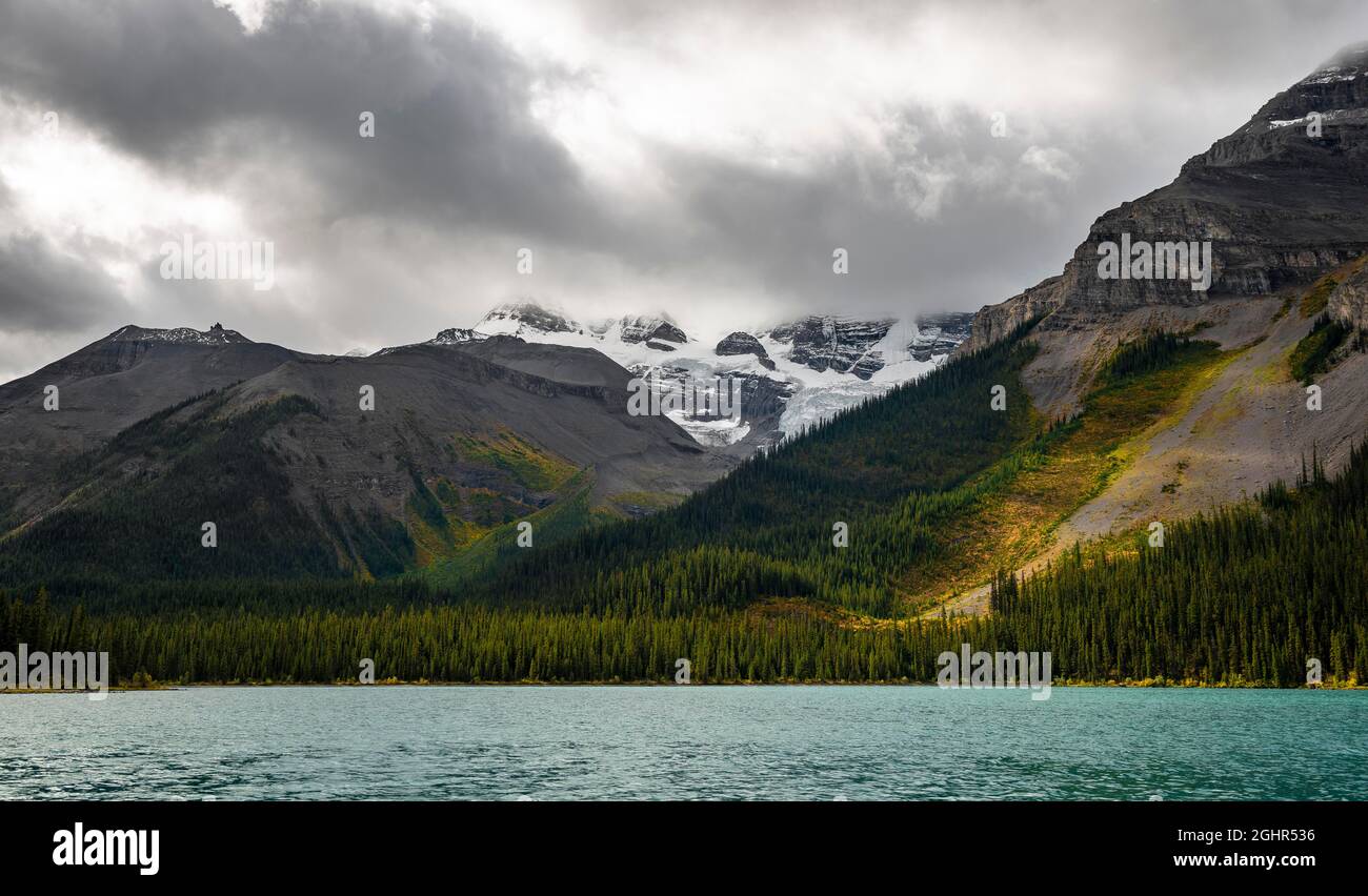 Sommets enneigés nuageux, Mont Charlton et Mont Unwin, forêt automnale, Lac Maligne, Alberta, Canada Banque D'Images