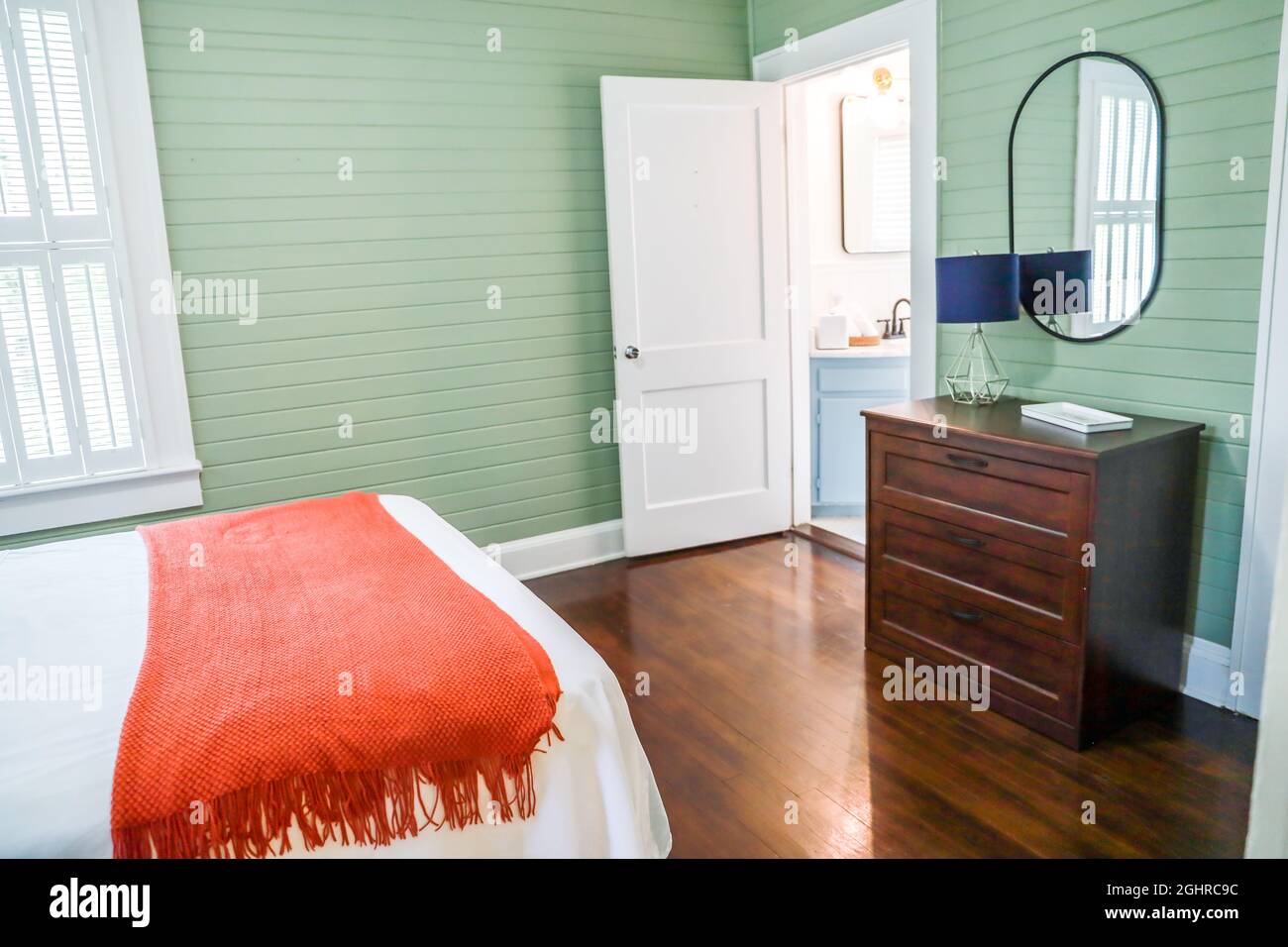 Une commode simple en bois sombre dans une chambre d'hôtes avec des murs en  panneaux verts et un miroir à rebord noir et une petite lampe Photo Stock -  Alamy