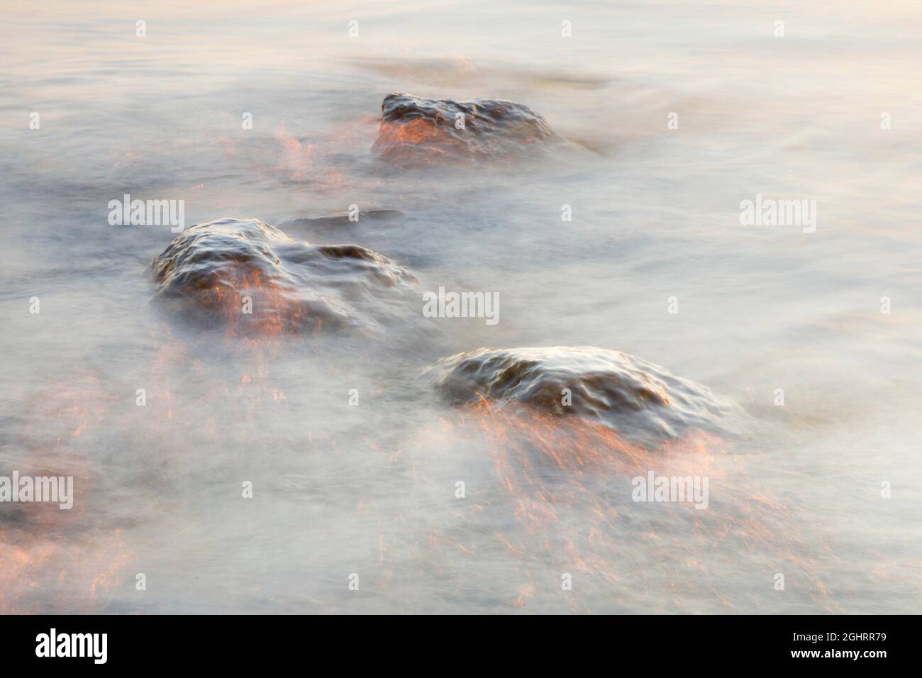 Jeu léger et pierres dans l'eau au lever du soleil photographiées à vitesse d'obturation lente, Lac de Constance près d'Arbon, Suisse Banque D'Images