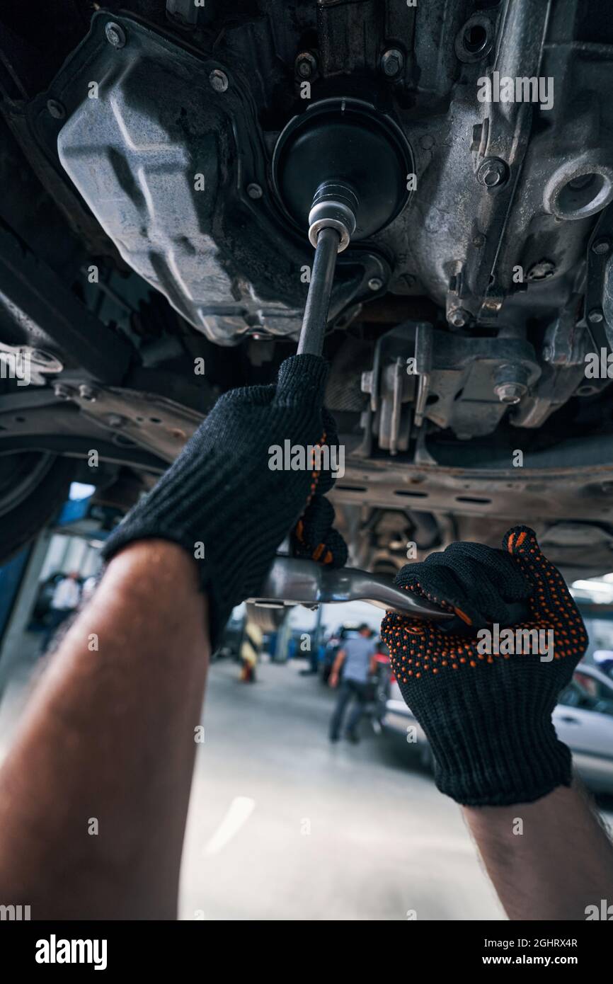 Personne sous la voiture utilisant une clé à douille pour effectuer le contrôle Banque D'Images