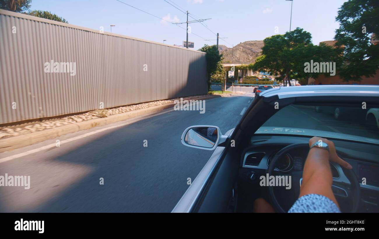 Benidorm, Espagne 18.08.2021 - vue arrière de la main de l'homme conduisant une voiture blanche sans toit sur la route. En portant une montre, la main sur la direction. Films de jour. Arbres sur le bord de la route. Banque D'Images