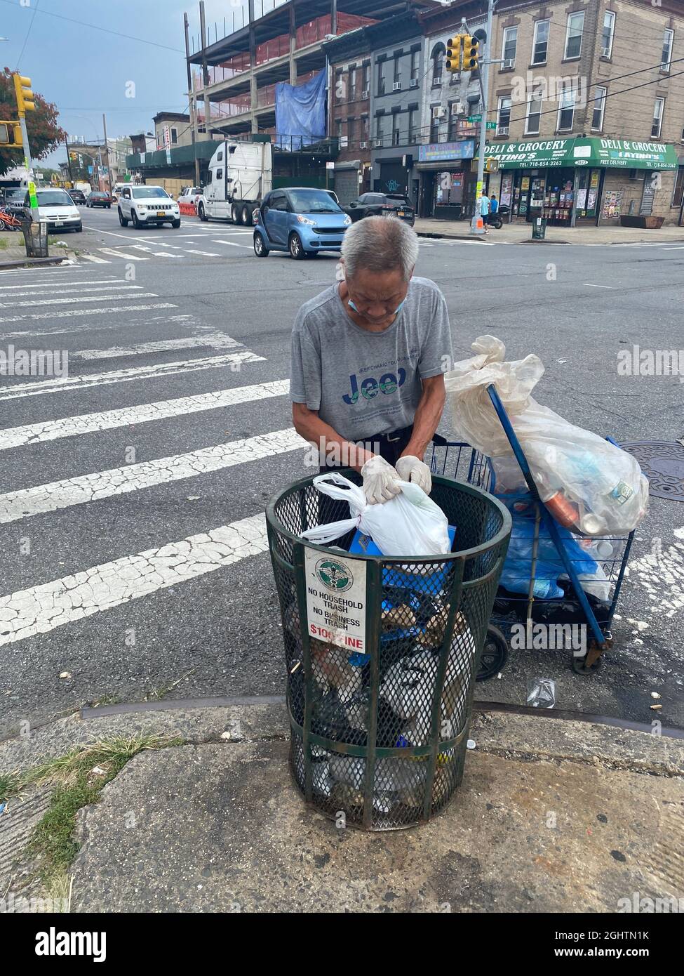 Homme chinois qui passe par une poubelle pour récupérer des boîtes en aluminium pour les récupérer sur fort Hamilton Parkway à Brooklyn, New York. Banque D'Images