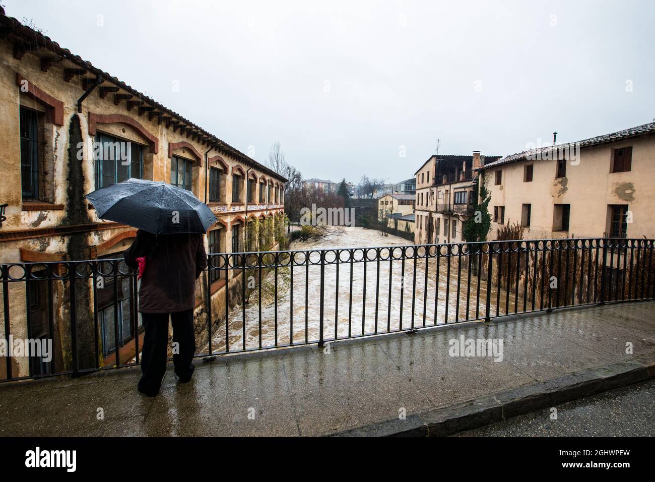 Vue arrière d'un homme debout sur un pont qui regarde les eaux d'inondation, Olot, la Garrotxa, Gérone, Espagne Banque D'Images