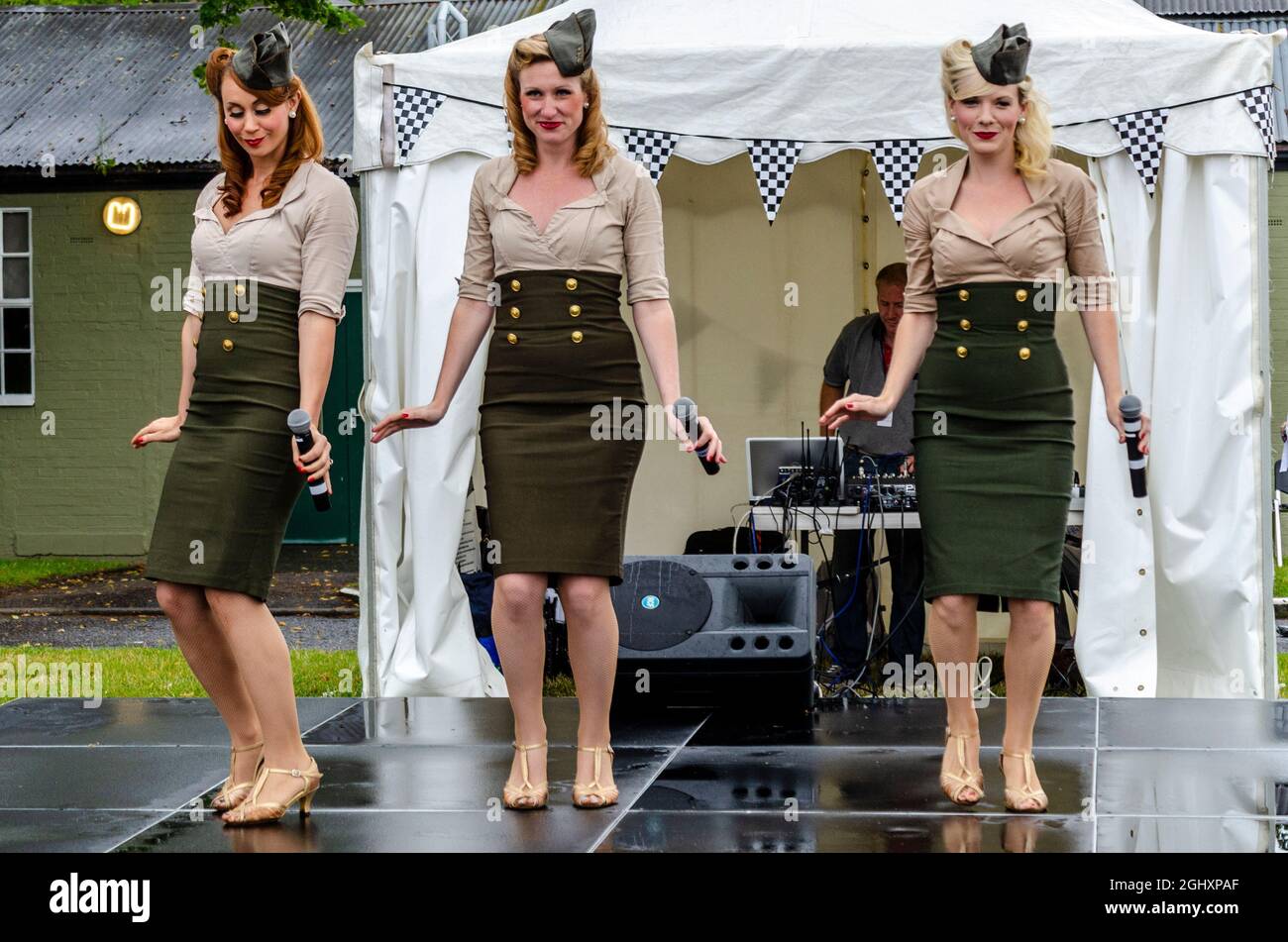 Les poupées de Manhattan chantent en Angleterre lors d'un événement de renouveau militaire. Chanteuses américaines en visite au Royaume-Uni, en train de jouer sous la pluie en portant des uniformes USAAF Banque D'Images