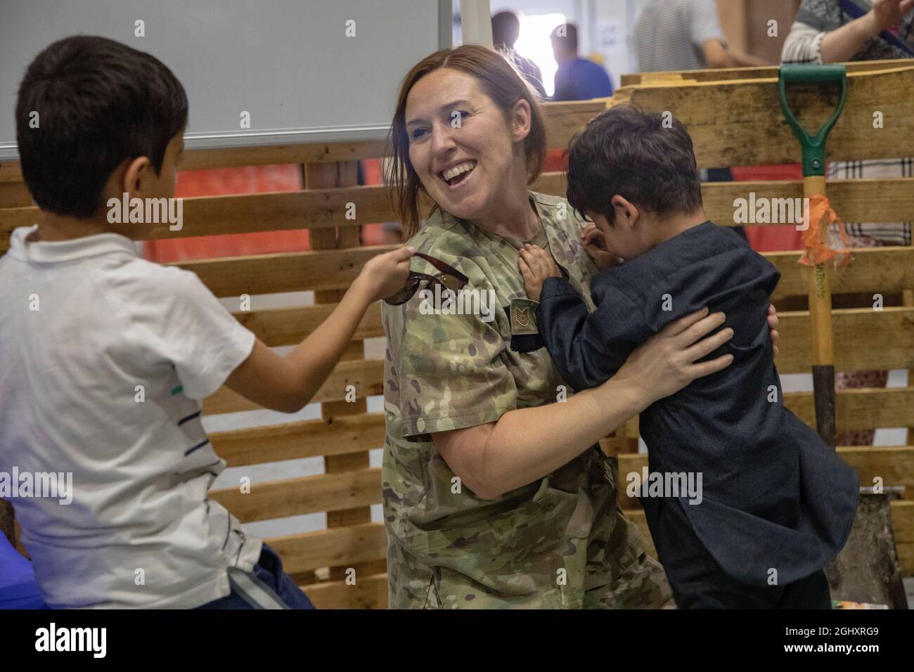 Un enfant afghan joue avec le Sgt de la U.S. Air Force Tech. Jennifer Sherrill, une médaillée de la 386e Escadre aérienne expéditionnaire, à la base aérienne Al Udeid, Qatar, le 28 août 2021. Les membres du ministère de la Défense continuent de saisir toutes les occasions d'appuyer les efforts d'évacuation du ministère d'État et de l'Afghanistan dans tout le théâtre du Commandement central des États-Unis. (É.-U. Photo de l'armée par la SPC. Huth Maximilian) Banque D'Images