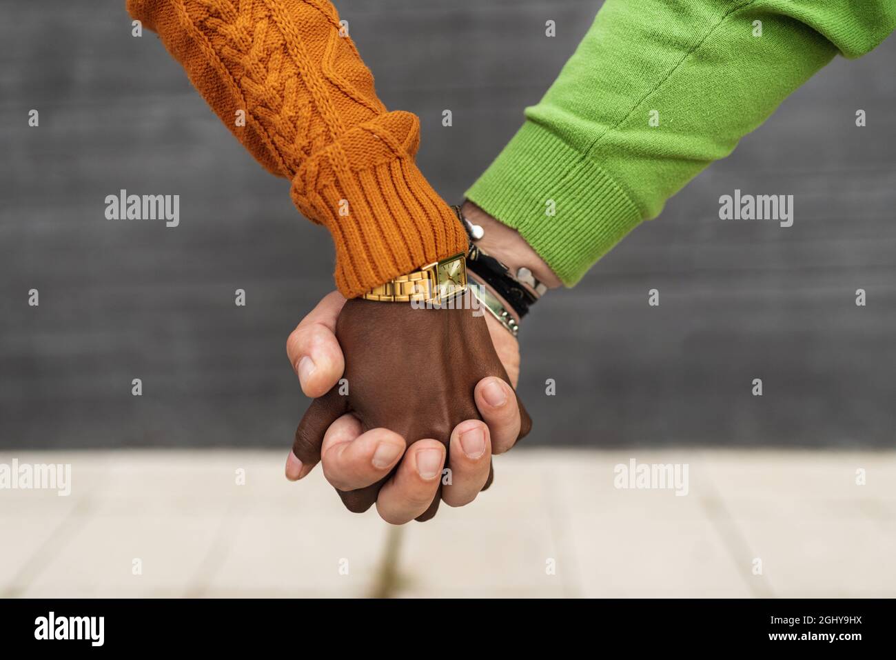 Vue rapprochée d'un couple interracial tenant les mains à l'extérieur dans la rue. Banque D'Images