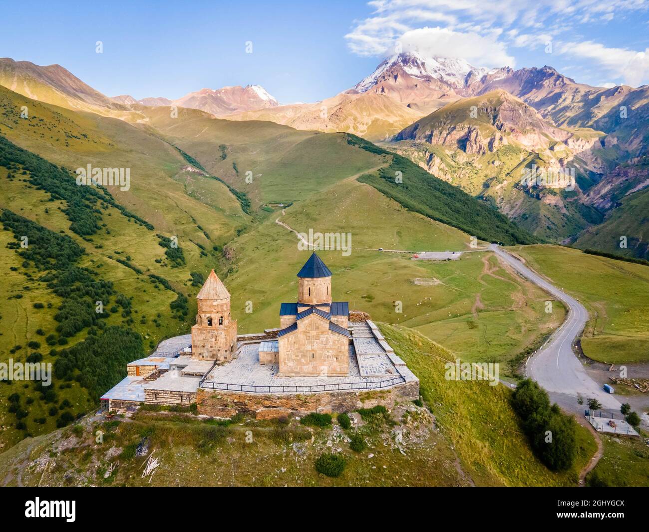 Vue aérienne rapprochée de la montagne Kazbek et de l'église de la Trinité de Gergeti en Géorgie au lever du soleil en été Banque D'Images