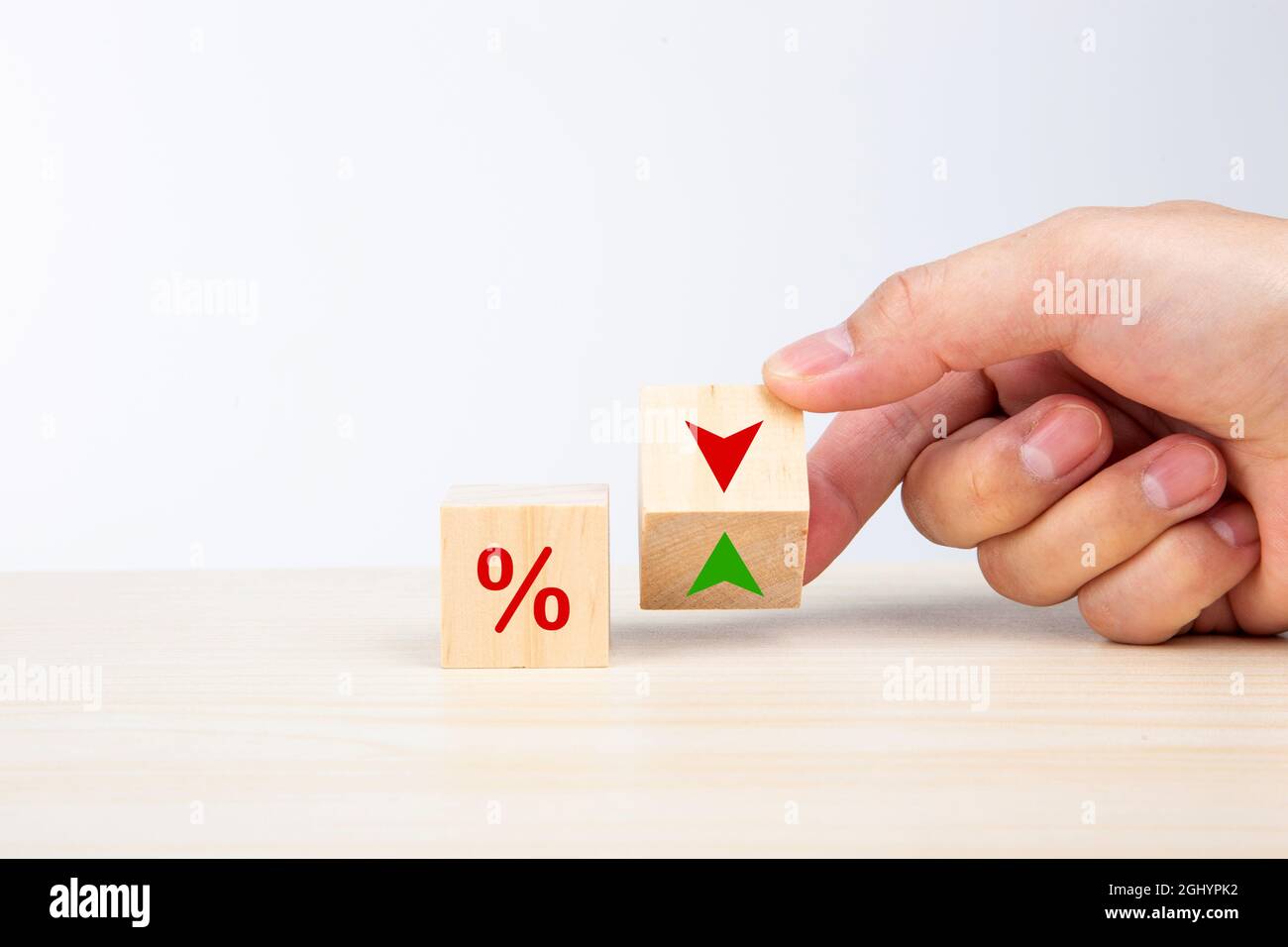 Concept de taux d'intérêt financier et hypothécaire. Tournez à la main la flèche de changement de cube en bois vers le bas vers le haut Banque D'Images