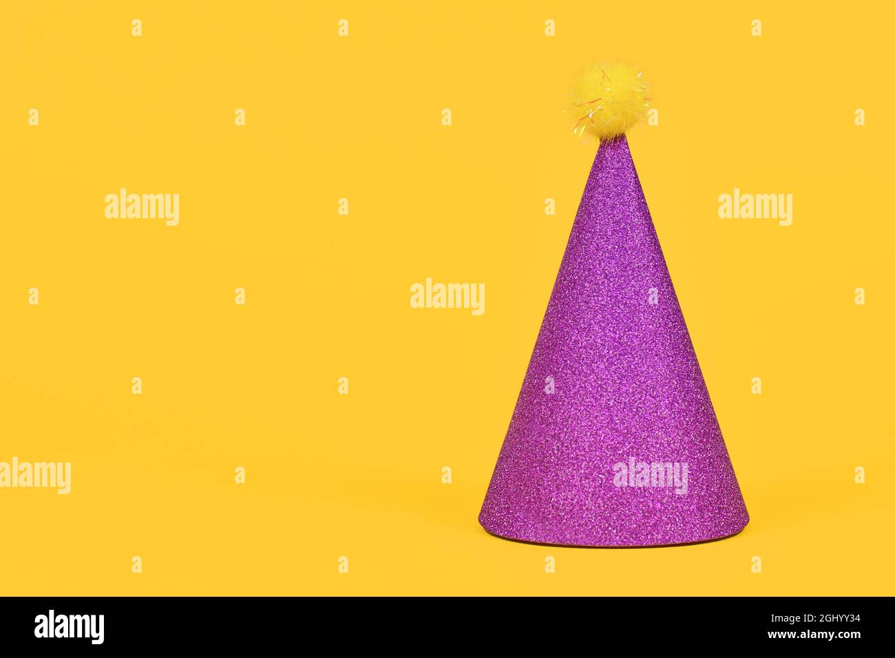 Chapeau de fête violet étincelant sur fond jaune avec espace pour les copies Banque D'Images Chapeau de fête violet étincelant sur fond jaune avec espace pour les copies Banque D'Images