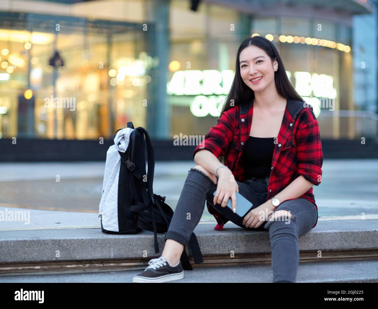 Attrayant asiatique hippster jeune femme voyageur solo avec sac à dos assis  sur les escaliers devant le centre commercial du centre-ville la nuit,  fille posant Photo Stock - Alamy
