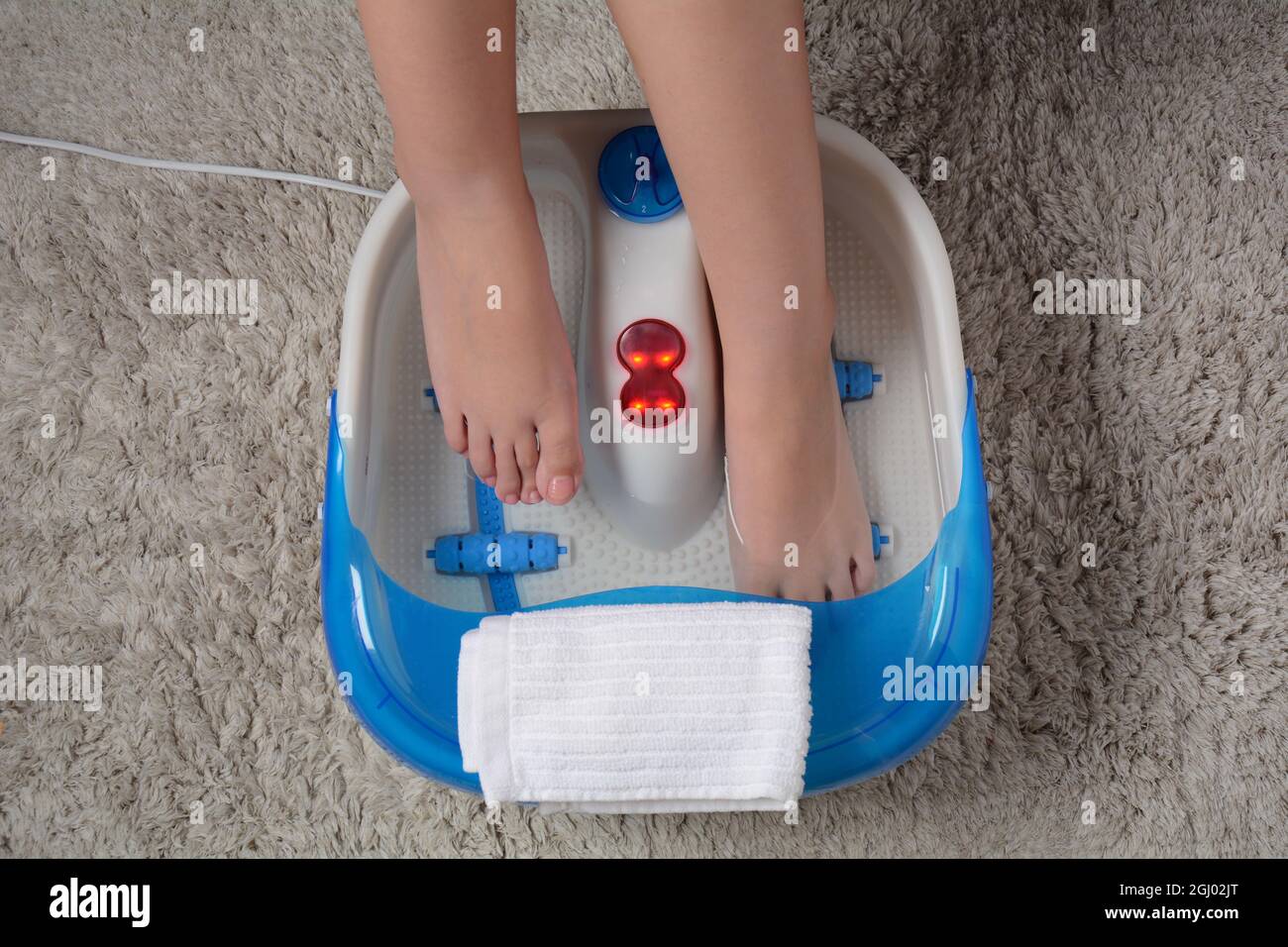 Pieds féminins dans un masseur vibrant. Bain de pieds à massage électrique. Détendez-vous après le travail. Pédicure et soins des pieds Banque D'Images