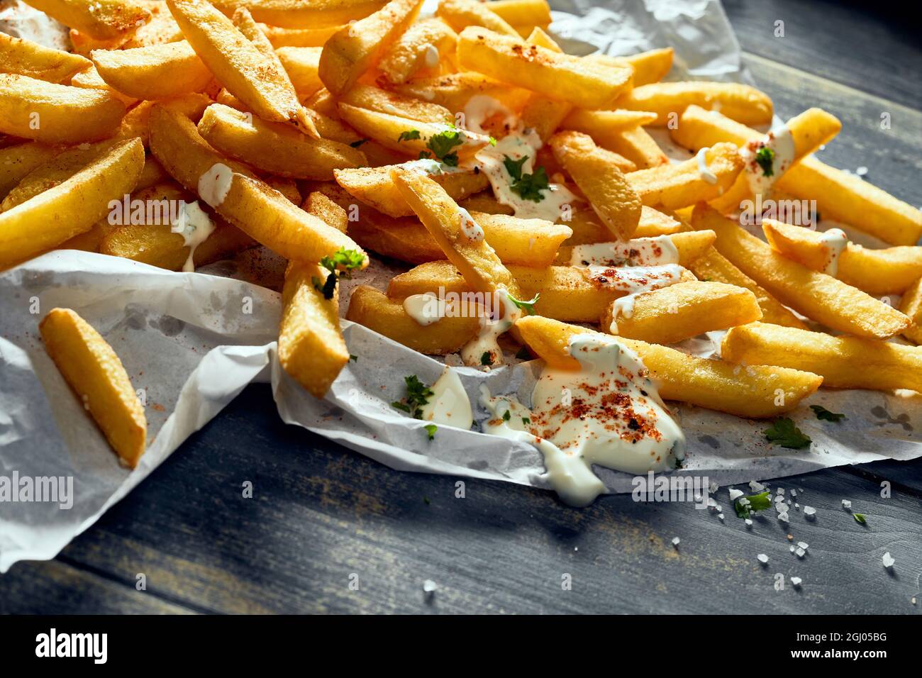 Grand angle de frites délicieuses avec crème sure et assaisonnements sur table en bois Banque D'Images