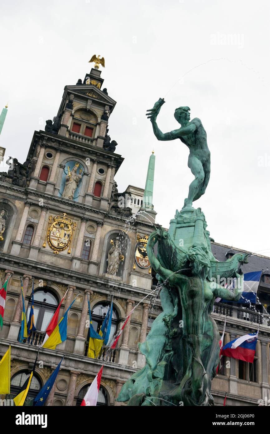 Statue de Brabo et main du géant avec l'hôtel de ville d'Anvers à Anvers lors d'une journée d'été nuageuse. Banque D'Images