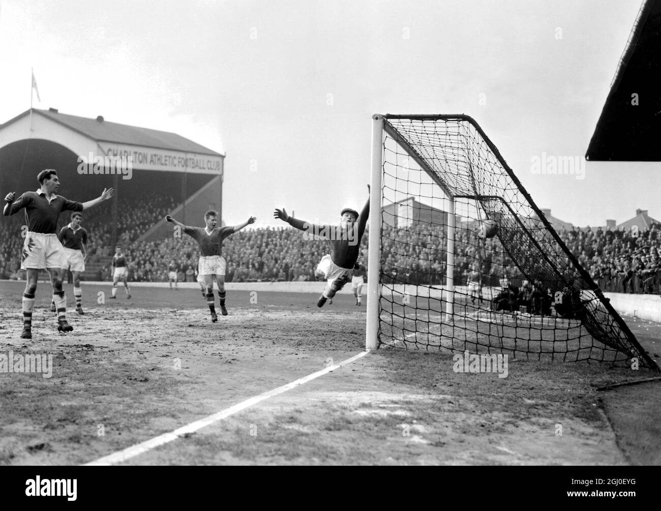 Charlton v Manchester United le deuxième but de Manchester United est marqué par le centre avant Tommy Taylor (pas sur la photo) avec une affiche supérieure lors du match de la division football League One contre Charlton Athletic à la Valley. Le gardien de but de Charlton William Duff, qui tente vaine de sauver le ballon, est le gardien de but de Manchester United Bill Whelan (au centre), qui lève ses bras avec joie. 18 février 1957 Banque D'Images