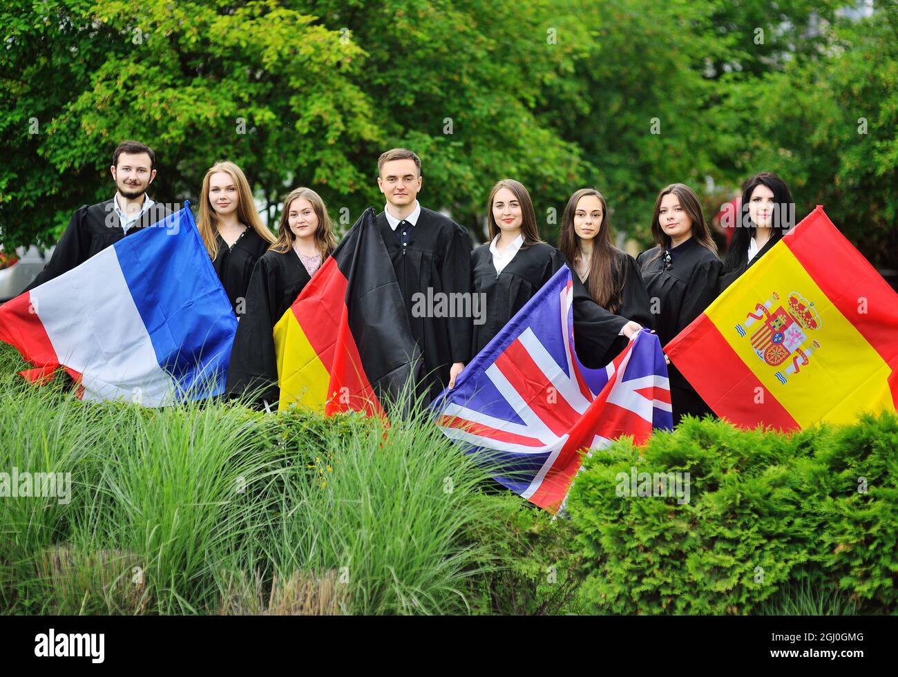 Groupe d'étudiants de la Faculté des langues étrangères diplômés en robes tiennent les drapeaux de la Grande-Bretagne, de la France, de l'Espagne et de l'Allemagne entre leurs mains. Banque D'Images