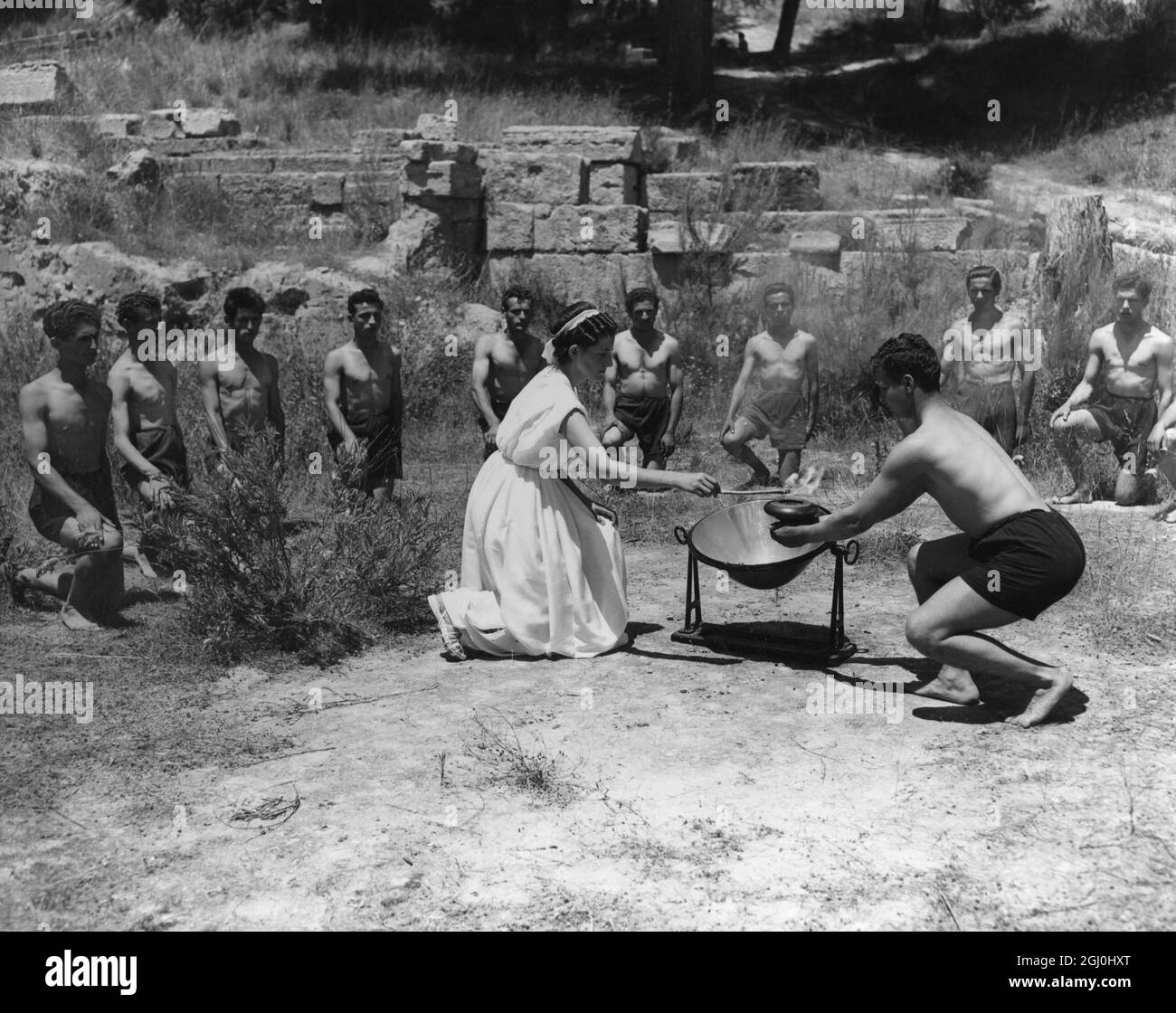 La flamme olympique est allumée. Dans les ruines du Temple de Zeus à Olympia, dans le sud de la Grèce, lorsque le soleil a atteint son zénith, une branche d'olive flamboyante tenue par une fille grecque rodée est utilisée pour éclairer la flamme olympique dans une ancienne lampe du Musée archéologique grec. 18 juillet 1948 Banque D'Images