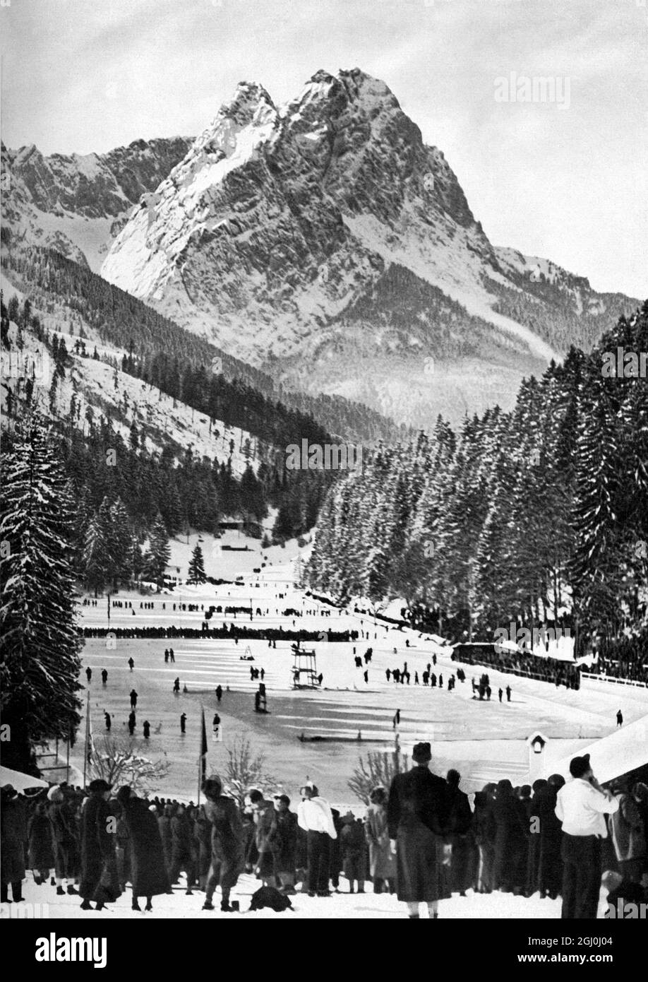 Sur le Riessersee près de Garmisch-Partenkirchen, les joueurs de hockey sur glace concourent dans la glace - des événements sportifs que pour la réunion olympique d'hiver a mis en scène dans un paysage d'hiver merveilleux en arrière-plan pour les nombreux spectateurs . TopFoto Banque D'Images