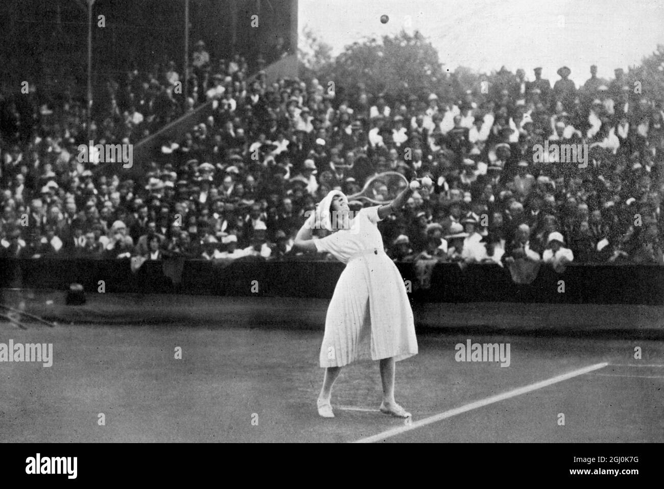 Défi des célibataires pour femmes : Mlle. Lenglen (challenger) au service en 1919. Suzanne Rachel flore Lenglen (24 mai 1899 - 4 juillet 1938) est une joueuse française de tennis qui a remporté 31 titres Grand Chelem de 1914 à 1926. Athlète flamboyante et tentatrice, elle a été la première célébrité féminine de tennis et l'une des premières stars internationales du sport féminin, nommée la Divine (la divine) par la presse française. ©TopFoto Banque D'Images