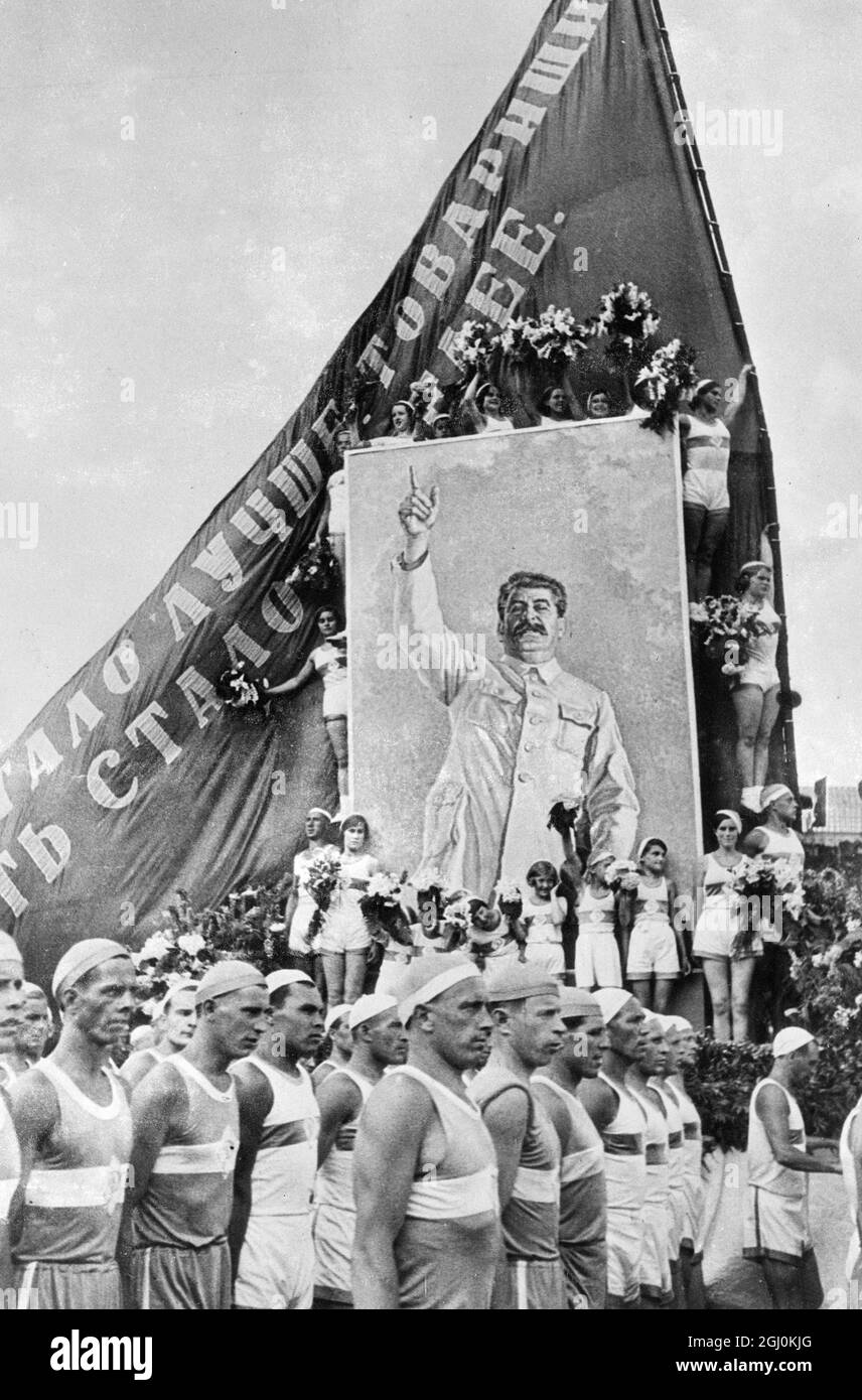 Les filles athlètes avec des fleurs ont encadré un portrait immense de Joseph Staline, dictateur soviétique qui a été défilé sur la place Rouge, Moscou, dans une grande parade de 75,000 athlètes et enfants en célébration de la Constitution soviétique. Les célébrations ont été les plus gayeuses jamais vues à Moscou depuis la Révolution, Selon le décret de Staline qui ''la vie est maintenant gayer et mieux''. 9 juillet 1936 Banque D'Images