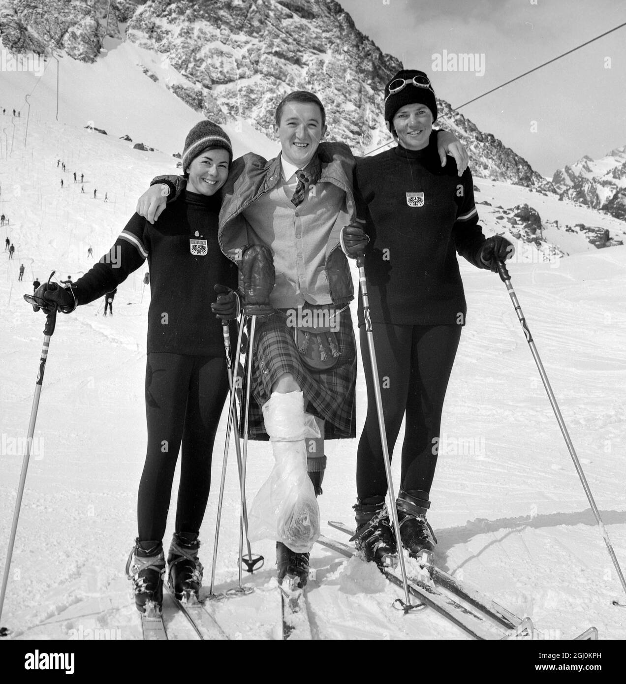 Portillo, Chili: Malgré une blessure, le skieur touristique écossais Ken Campbell est tout sourire alors qu'il pose avec les stars de ski autrichiennes Heidi Zimmermann et Traudl Hecher alors que les Championnats du monde de ski alpin de 1966 ont commencé à Portillo, au Chili, le 4 août. 160 skieurs de 22 pays, dont la Grande-Bretagne, participent aux championnats. 8 août 1966 Banque D'Images