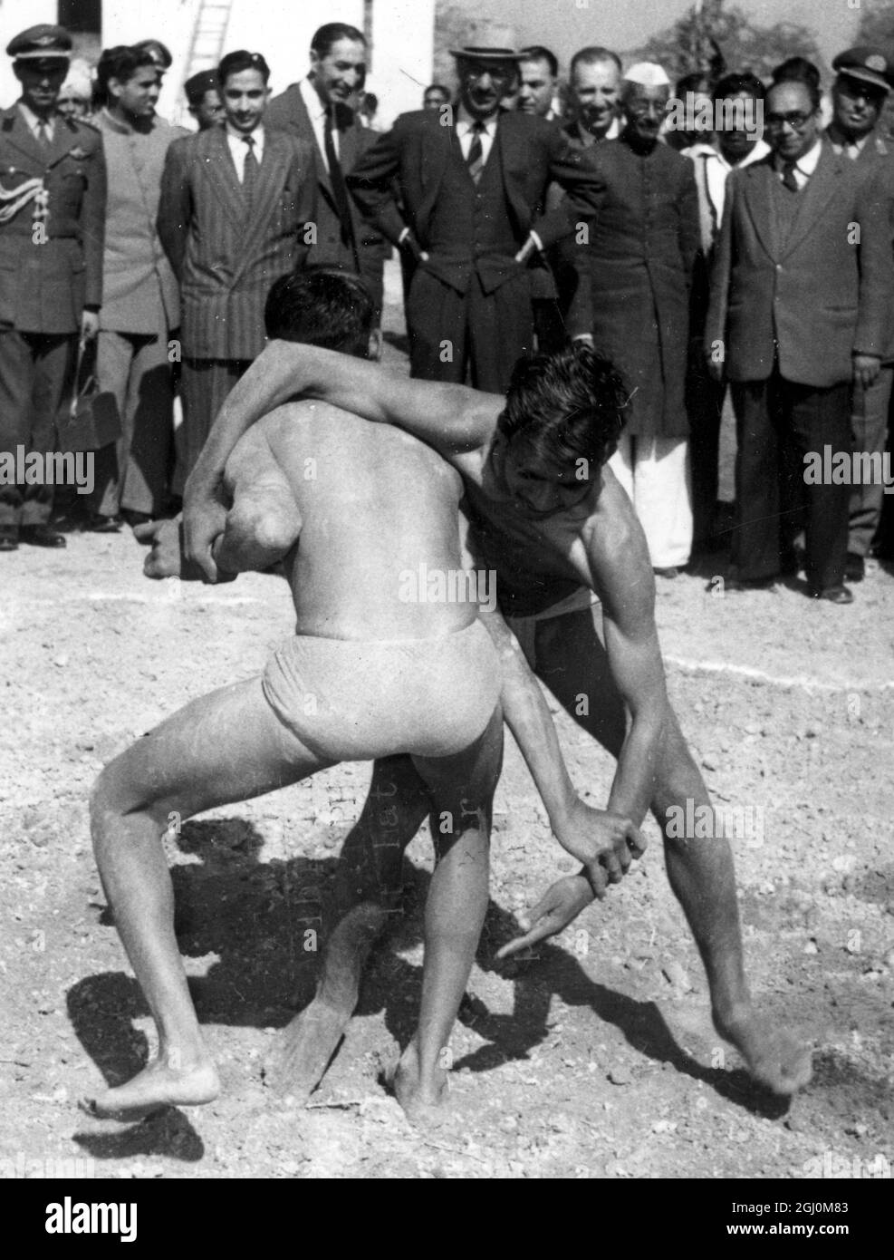 Roi d'Afghanistan portant un chapeau de feutre centre Backgound regardant une paire de lutteurs au centre communautaire à l'extérieur de New Delhi 18 février 1958 Banque D'Images