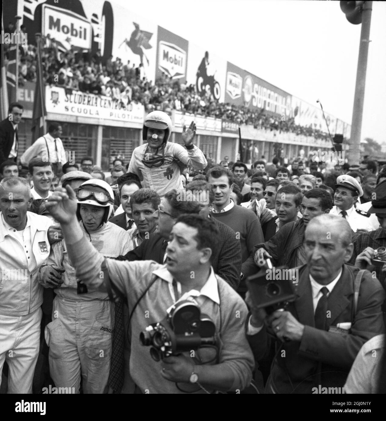 John Surtees et Lorenzo Bandini sont emportés par des spectateurs après la fin du 35e Grand Prix d'Italie que Surtees a remporté dans une usine entrée dans Ferrari. Bandini a terminé troisième dans sa nouvelle usine Ferrari 12 cylindres derrière Bruce McLaren en Nouvelle-Zélande, qui a pris la deuxième place dans a Cooper. 8 septembre 1964. Banque D'Images