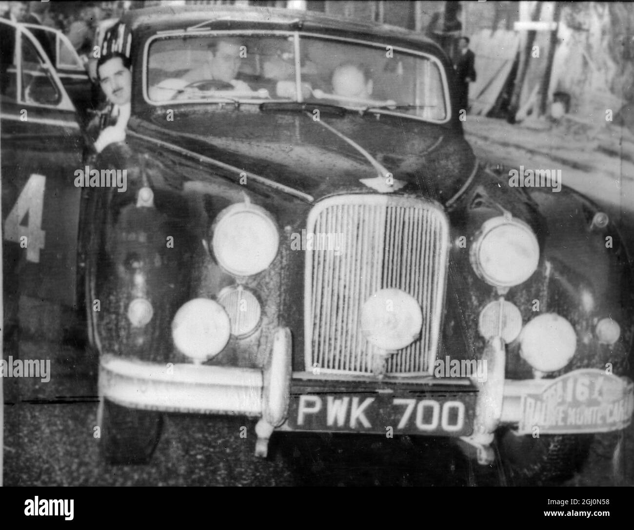 Monte Carlo : L'équipe britannique dans leur Jaguar qui a gagné le Monte Carlo Rally . se pencher hors de la porte de voiture est le conducteur , Ronald Adams de 35 ans, un ulsterman aussi dans la voiture sont ses co-pilotes , Frank Biggar un Dublin garage Manager et D . G . Johnstone . Adams , qui a commencé de Glasgow est le quatrième pilote britannique à gagner l'événement la dernière victoire britannique a été celle de Sydney Allard en 1952 . 22 janvier 1956 Banque D'Images
