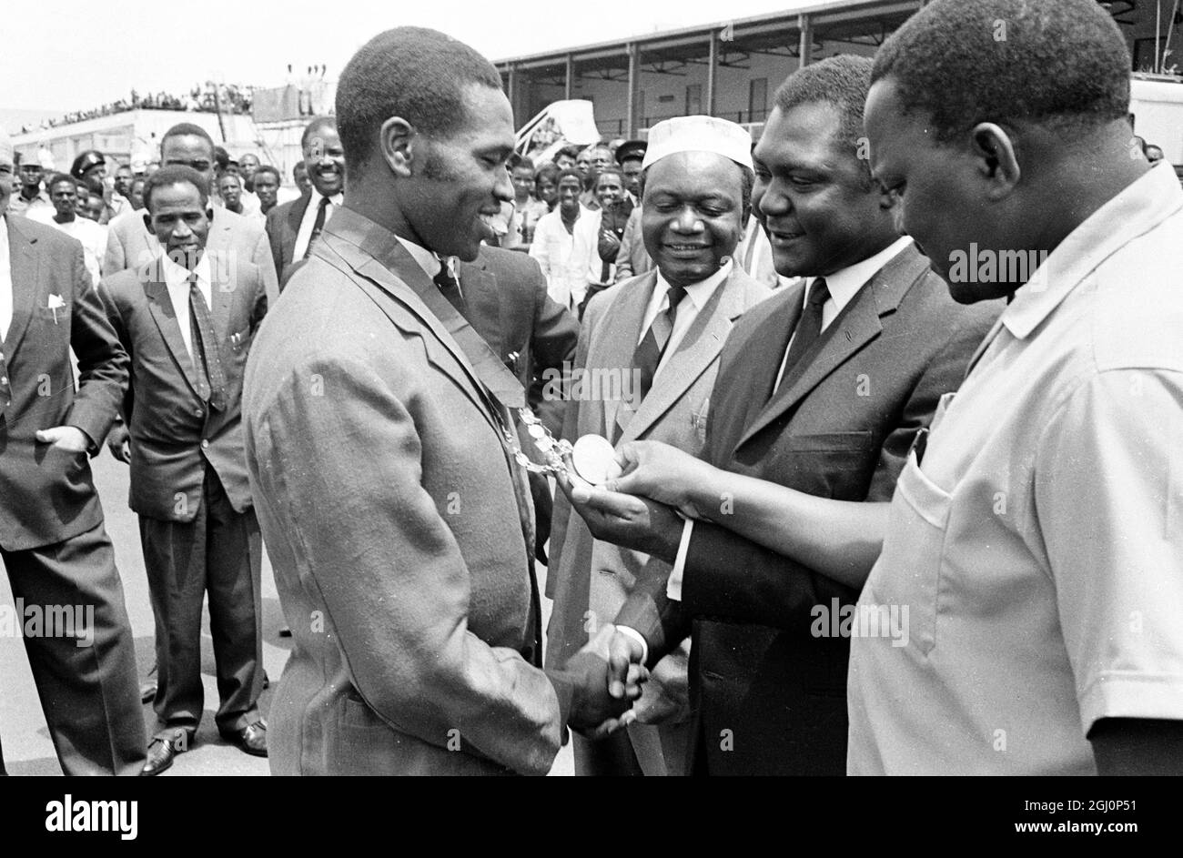 Les ministres kenyans Tom Mboya (deuxième de droite), ministre de la planification économique , et M. Paul Ngei (de droite), ministre du logement , examinent les médailles d'or remportées par Kipchaut Keino (de gauche) , coureur d'émerveillement kenyan , aux Jeux du Commonwealth à Kingston (Jamaïque) . Cette photo a été prise le 22 août 1966 alors que l'équipe kenyane renait triomphant à Nairobi . Keino a gagné les golds pour les deux Mile et les trois Miles . 24 août 1966 Banque D'Images