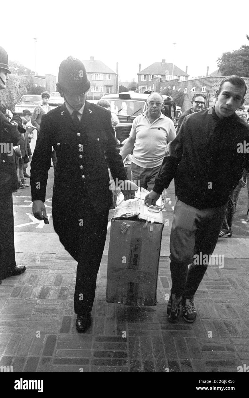 Welwyn Garden City, Herts : Horst Hottges en Allemagne de l'Ouest est photographié avec l'aide d'un policier britannique pour transporter un colis à l'hôtel Homstead court aujourd'hui. L'Allemagne de l'Ouest rencontrera l'Angleterre dans le dernier tournoi de la coupe du monde cet après-midi au stade Wembley. 30 juillet 1966 Banque D'Images