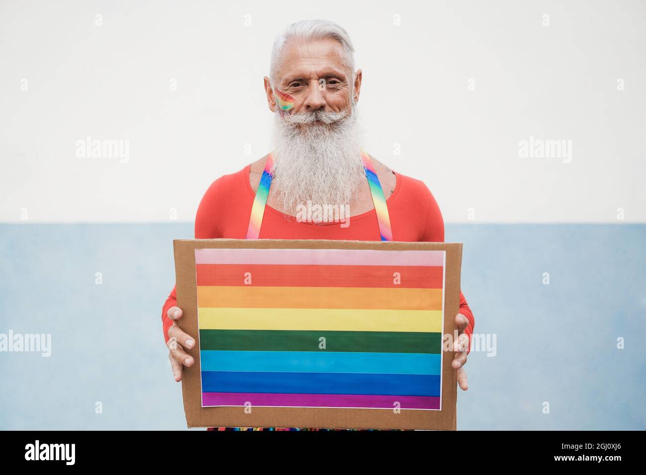 Hipster homme senior à la fierté gay tenant la bannière lgbt arc-en-ciel - Focus sur le visage Banque D'Images