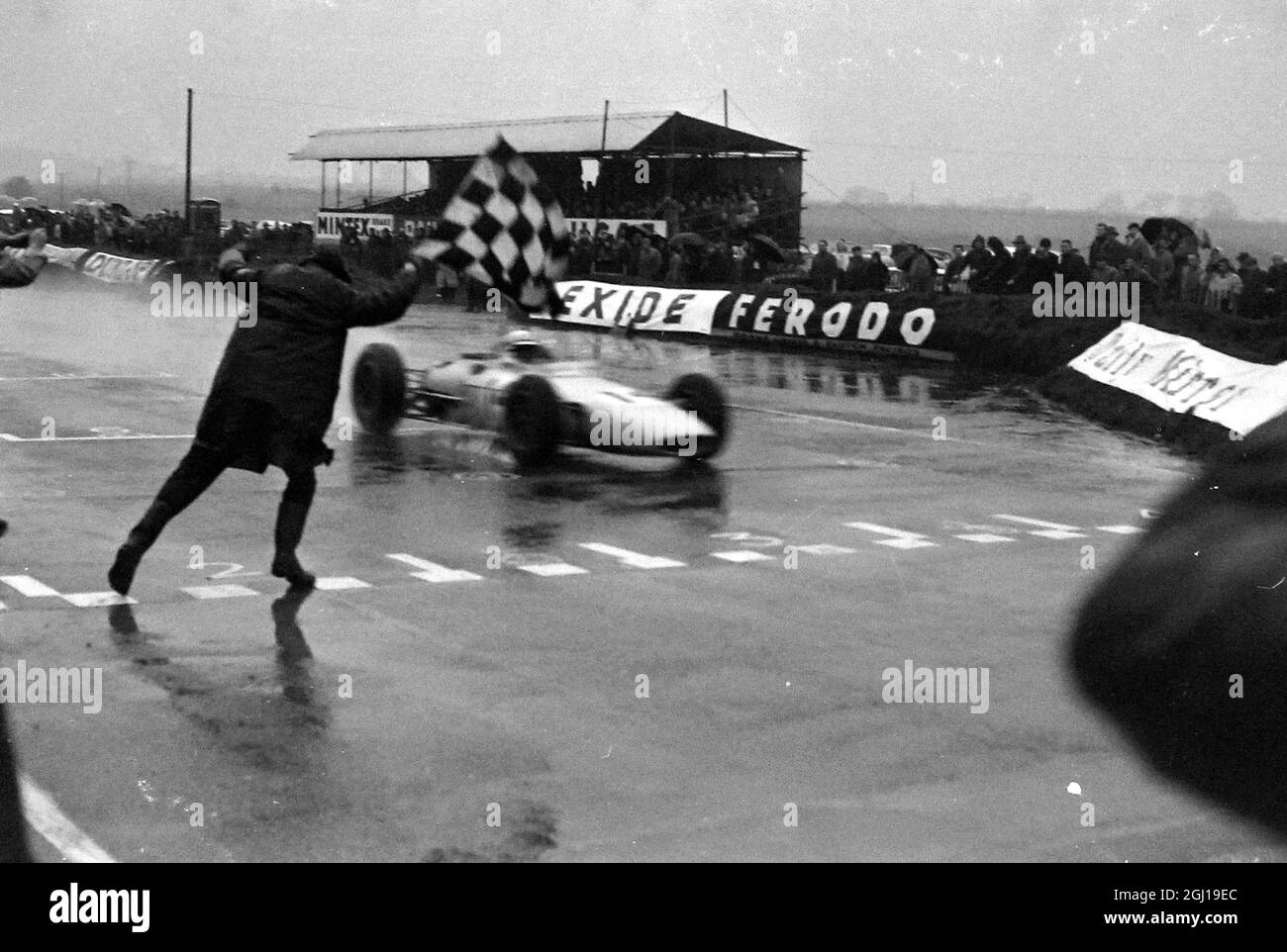 MOTOR CAR INTERNATIONAL FORMULA 1 - PILOTE DE COURSE INNES IRELAND À TRAVERS LA LIGNE D'ARRIVÉE À SNETTERTON ; 15 MARS 1964 Banque D'Images