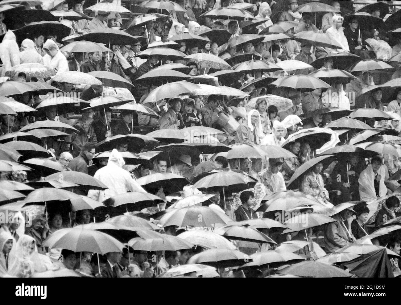 JEUX OLYMPIQUES, JEUX OLYMPIQUES DE SPORT - LA XVIII 18E OLYMPIADE À TOKYO, JAPON - LES SPECTATEURS ÉLÈVENT DES PARAPLUIES ALORS QUE LA PLUIE DÉVERSE ; 15 OCTOBRE 1964 Banque D'Images