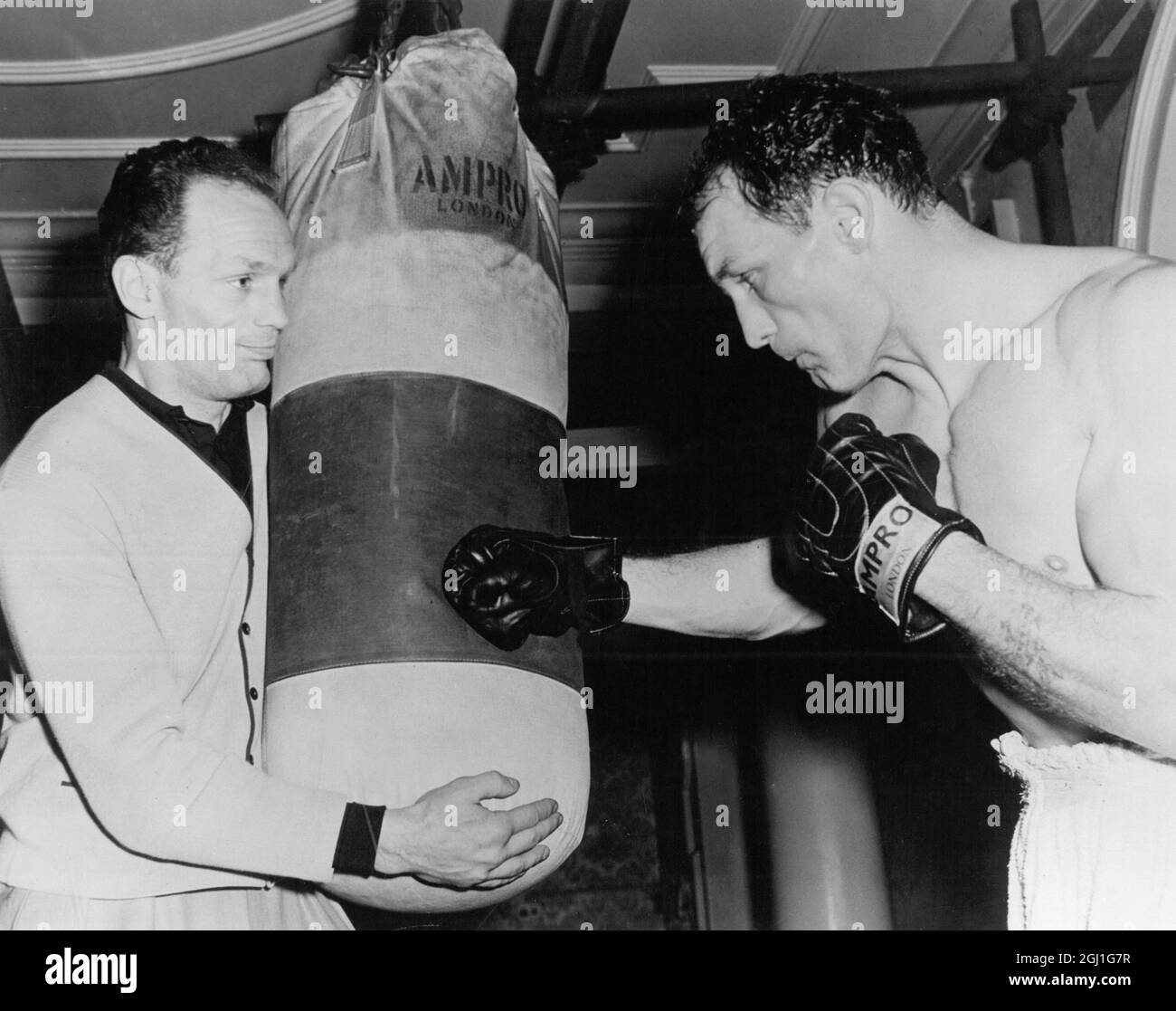 Henry Cooper ( à droite ) reçoit l'aide de son frère Jim , lors d'une session de formation sur le sac de punch lourd . 2 mars 1963 Banque D'Images