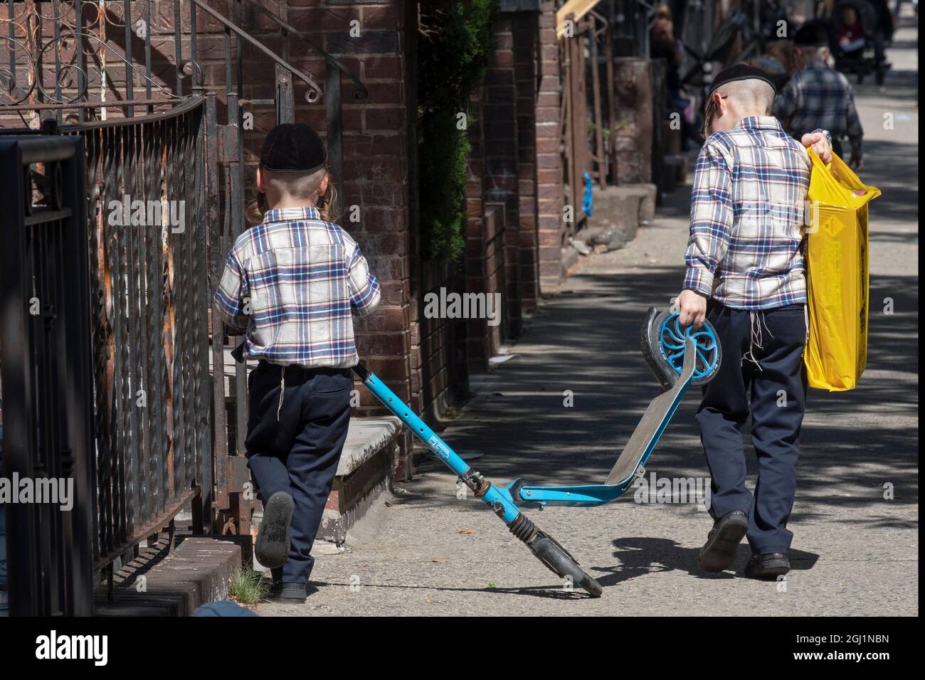 Les frères juifs orthodoxes vêtus portent leur scooter à la maison d'une manière inhabituelle. À Williamsburg, Brooklyn, New York. Banque D'Images