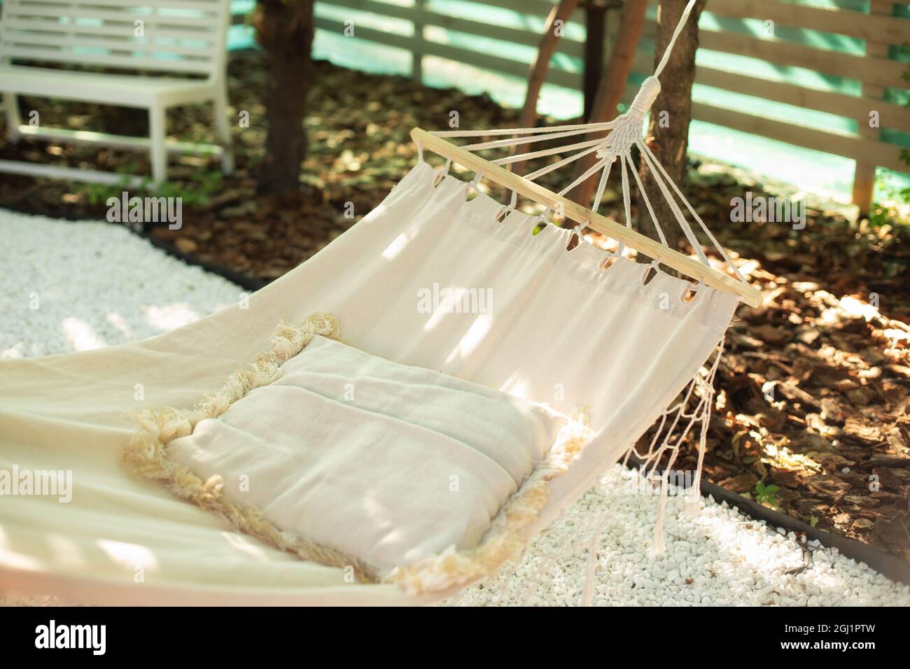 Hamac blanc et oreiller pour se détendre à l'ombre du jardin de l'arrière-cour l'après-midi d'été.Hamac confortable de style bohémien avec oreiller suspendu sur l'arbre. Banque D'Images