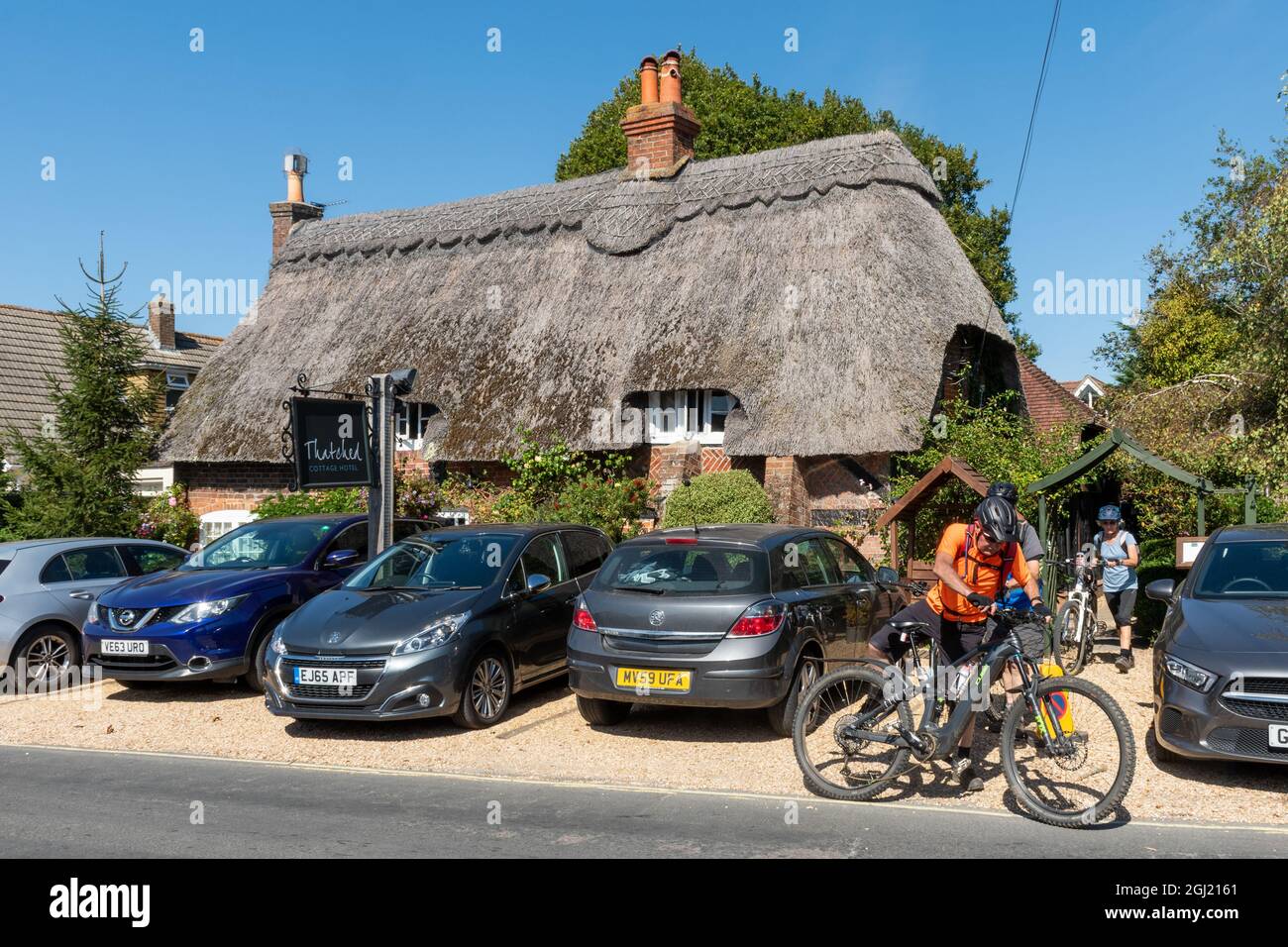 Cyclistes à l'extérieur du thatched Cottage Hotel dans le village New Forest de Brockenhurst, Hampshire, Angleterre, Royaume-Uni Banque D'Images