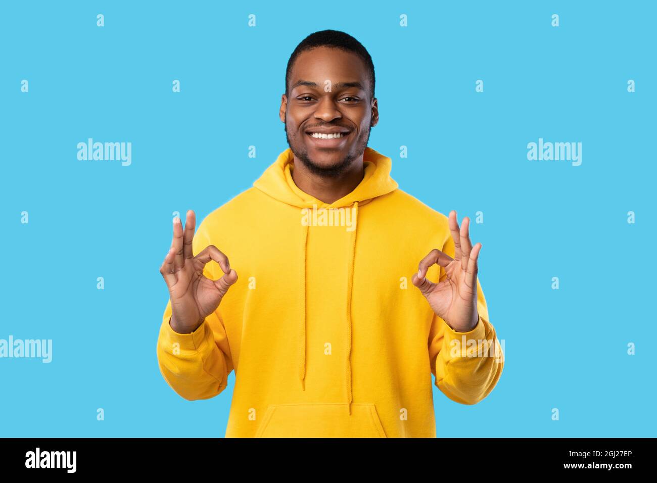 Tout est OK. Sourire Africain américain Guy gesturant OK signe avec les  deux mains regardant la caméra debout sur fond bleu, portant lumineux Yello  Photo Stock - Alamy
