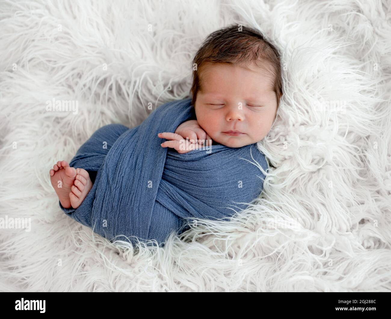 Nouveau-né bébé garçon dormant dans un tissu sur fourrure blanche. Portrait  de studio pour bébé avec décoration Photo Stock - Alamy
