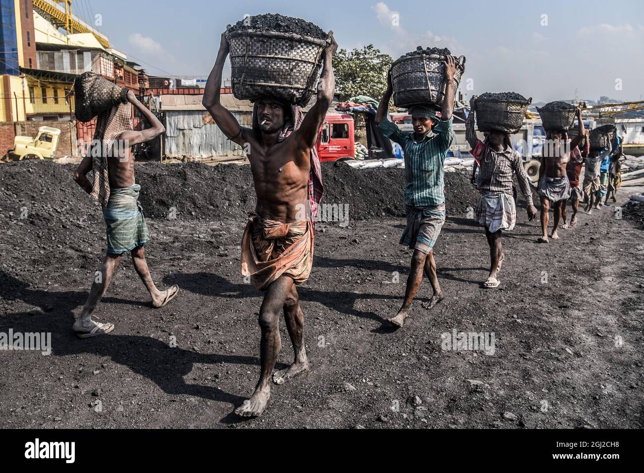 Hommes et femmes travailleurs quotidiens déchargeant des charbons de petits navires dans la ville portuaire du fleuve Karnabuli, Chittagong, Bangladesh. Banque D'Images