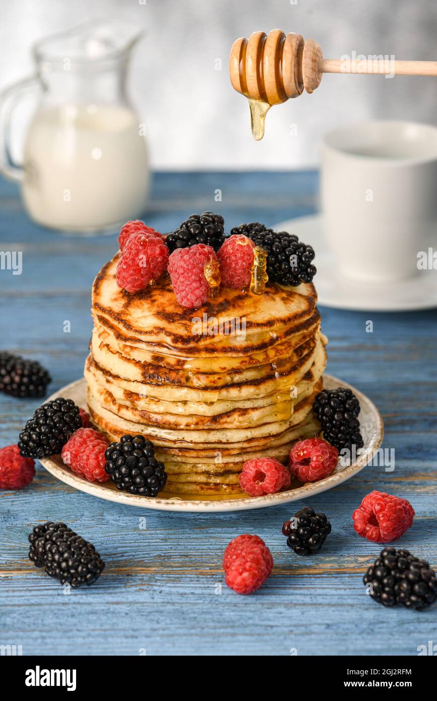 Crêpes américaines, baies éparpillées. Mûres, framboises. Plié dans une pile, arrosé de miel. Mise au point sélective. Banque D'Images