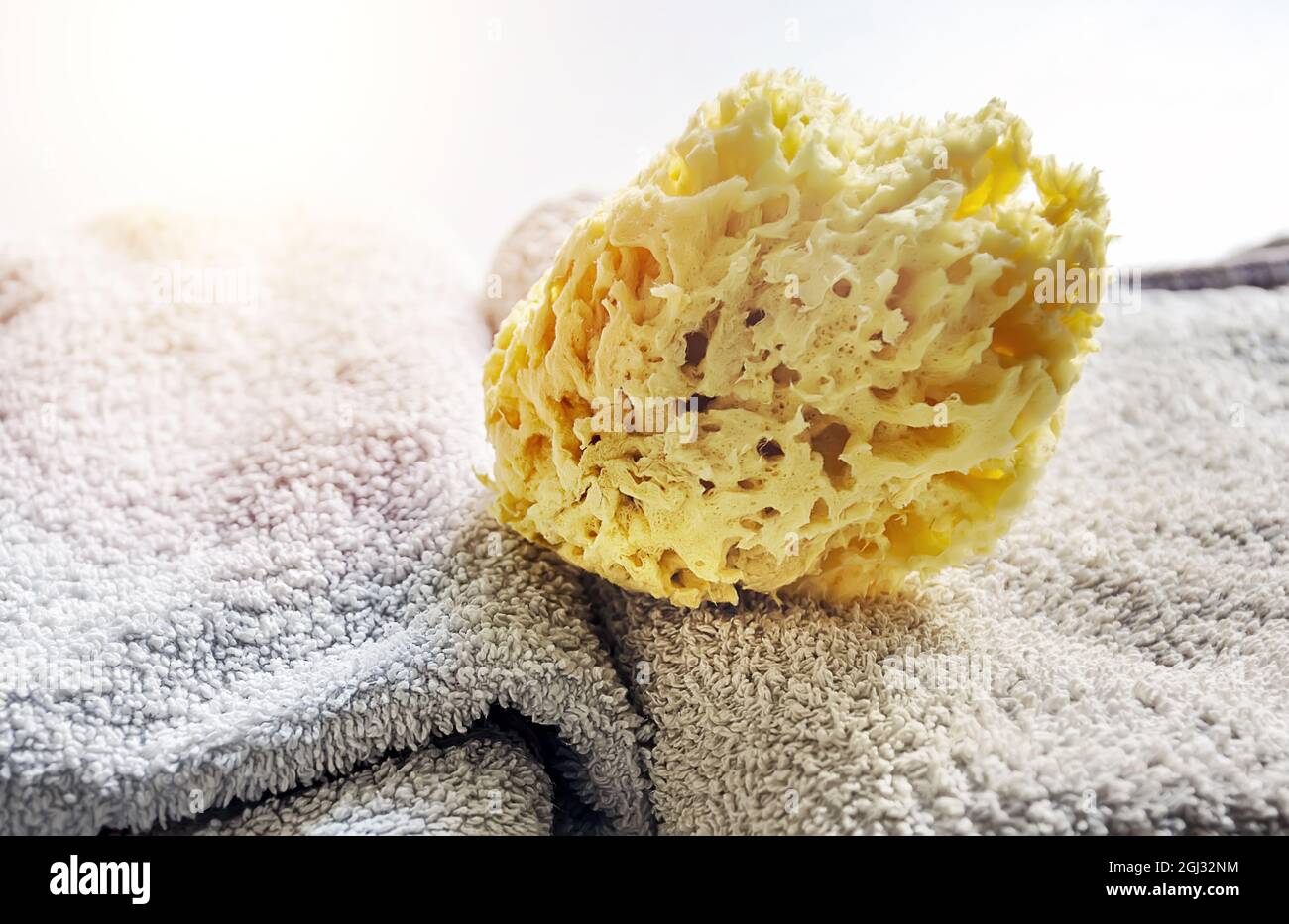 Éponge jaune naturel sur les serviettes empilées. Soins personnels et hygiène. Bain et détente Banque D'Images