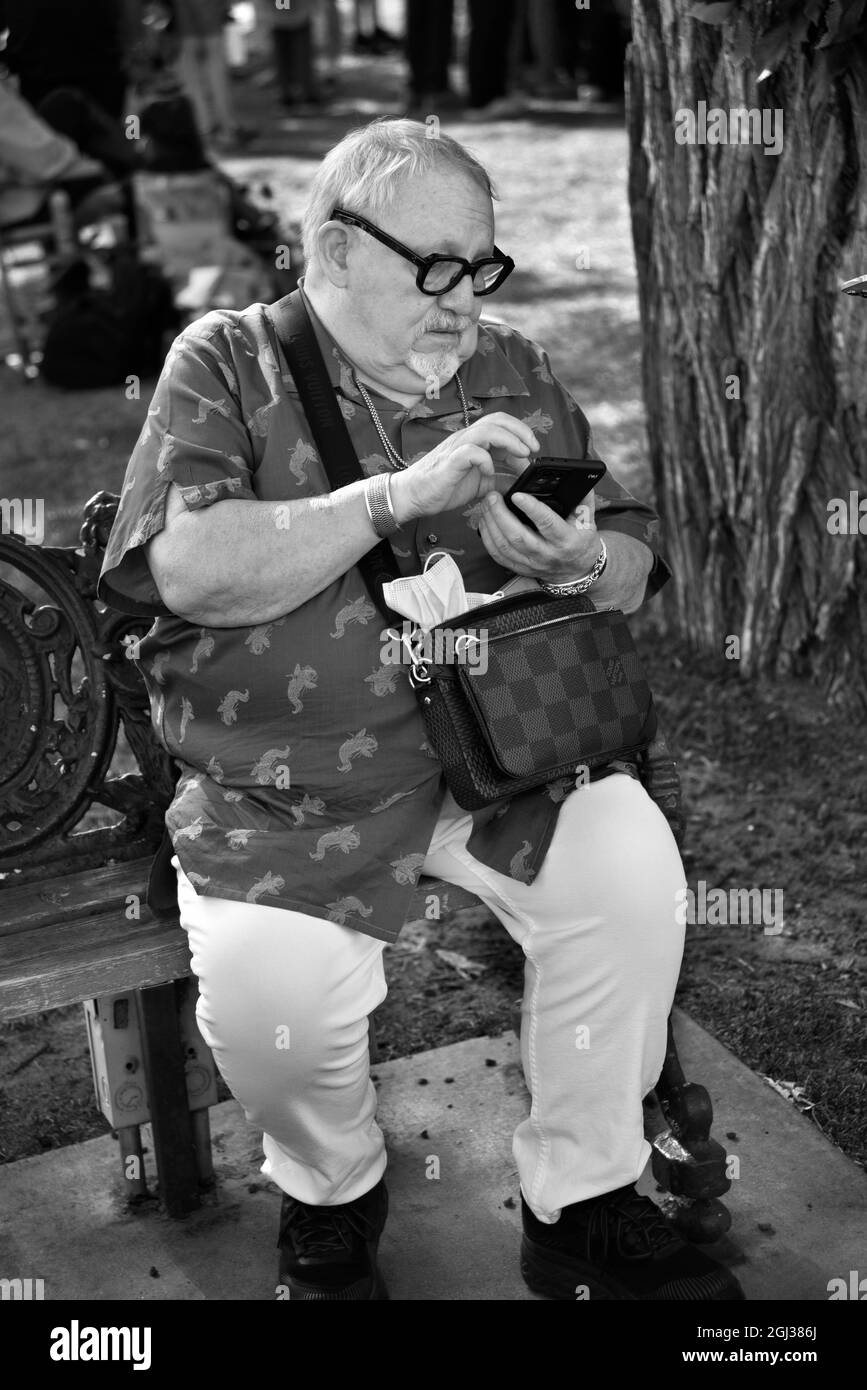 Un homme âgé qui visite Santa Fe, au Nouveau-Mexique, utilise son smartphone tout en se relaxant dans un parc de Santa Fe, au Nouveau-Mexique. Banque D'Images